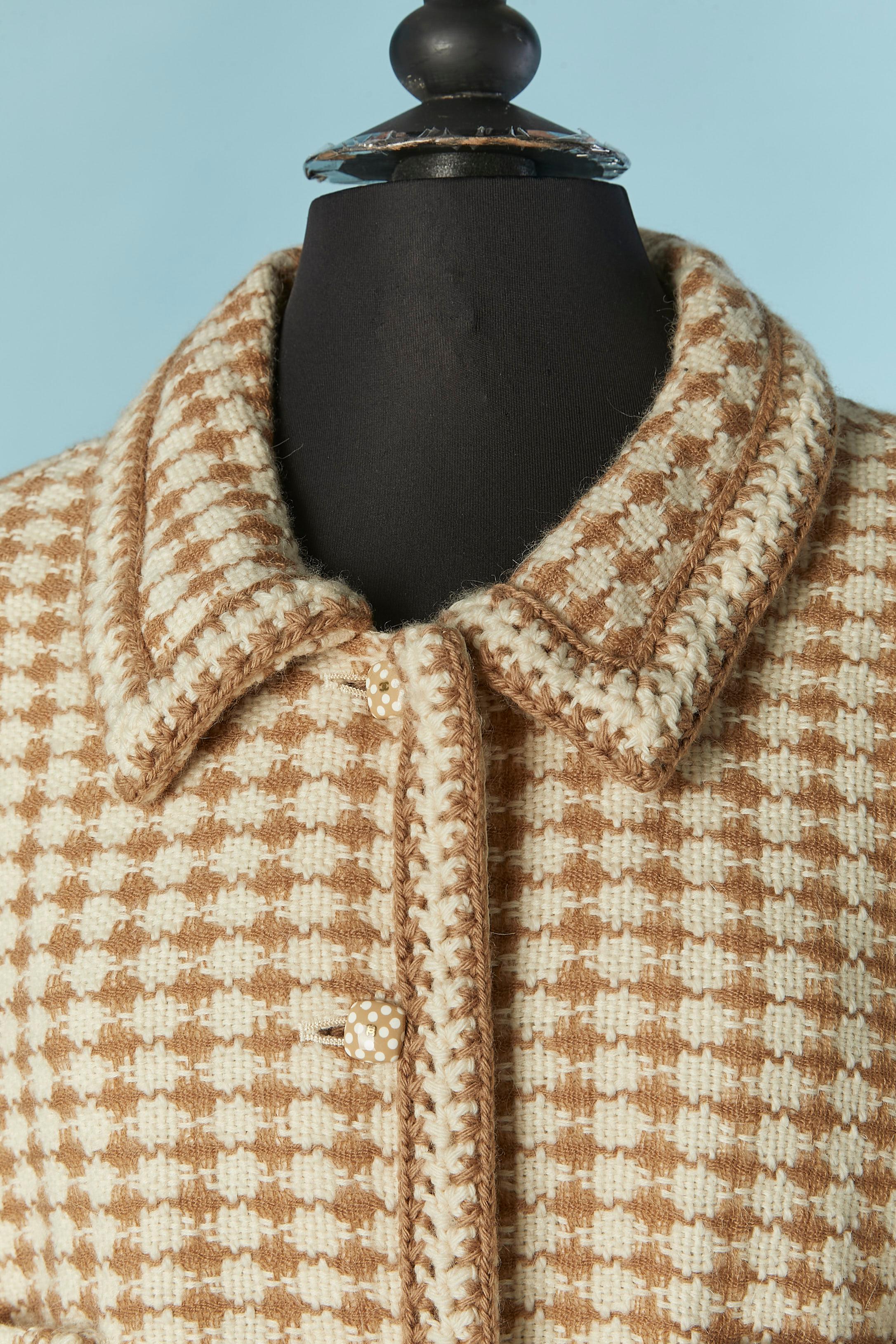 Veste longue en tweed marron et blanc cassé . Composition du tissu principal : 52% laine, 32% alpaga, 16% mohair. Doublure en soie. 
Pad d'épaule. Fermeture par bouton et boutonnière sur le milieu du devant. Poches sur la poitrine + 2 poches de