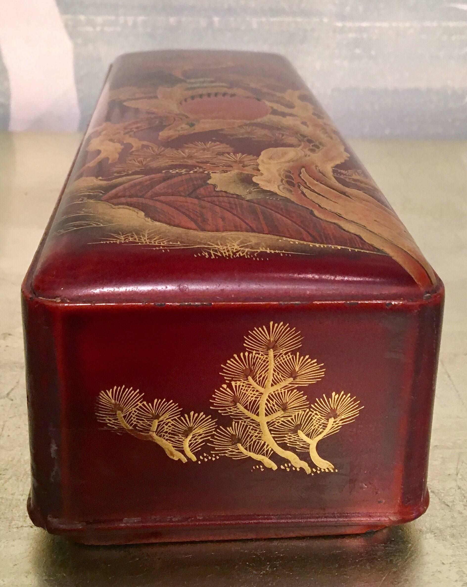 A brown and red lacquer box with design of hawk, pine tree and river.