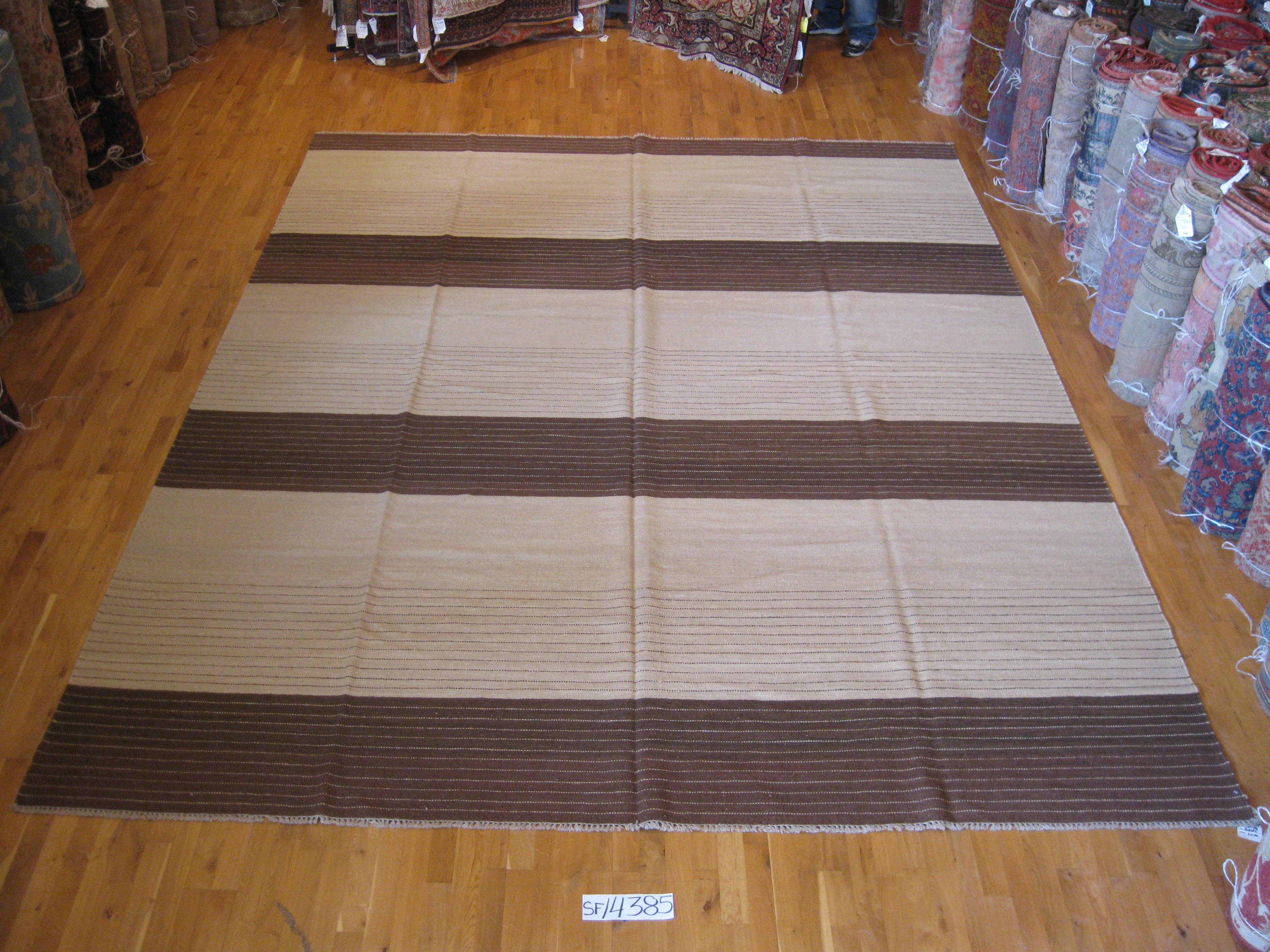 Simple design with big impact. Kilims are the most versatile of rugs: Reversible, easy to move and easy to clean. Bold brown and tan color blocks in this large wool piece contain thin reverse striping.