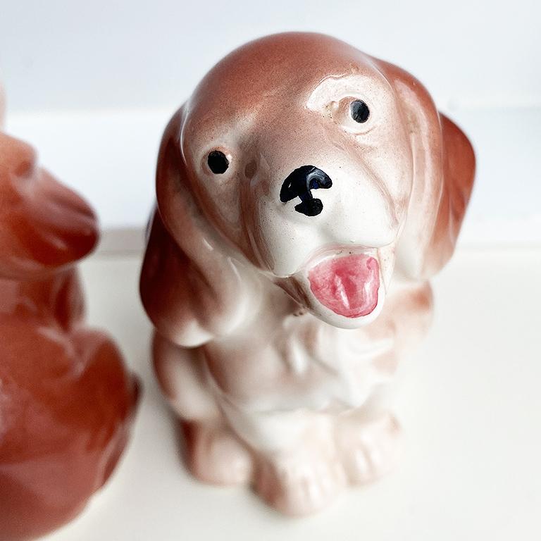 A pair of brown and white ceramic dog salt and pepper shakers. Each shaker depicts a brown dog with black eyes and a pink tongue. They remind us a bit of the Staffordshire style. A perfect way to add a traditional touch to your next dinner party.