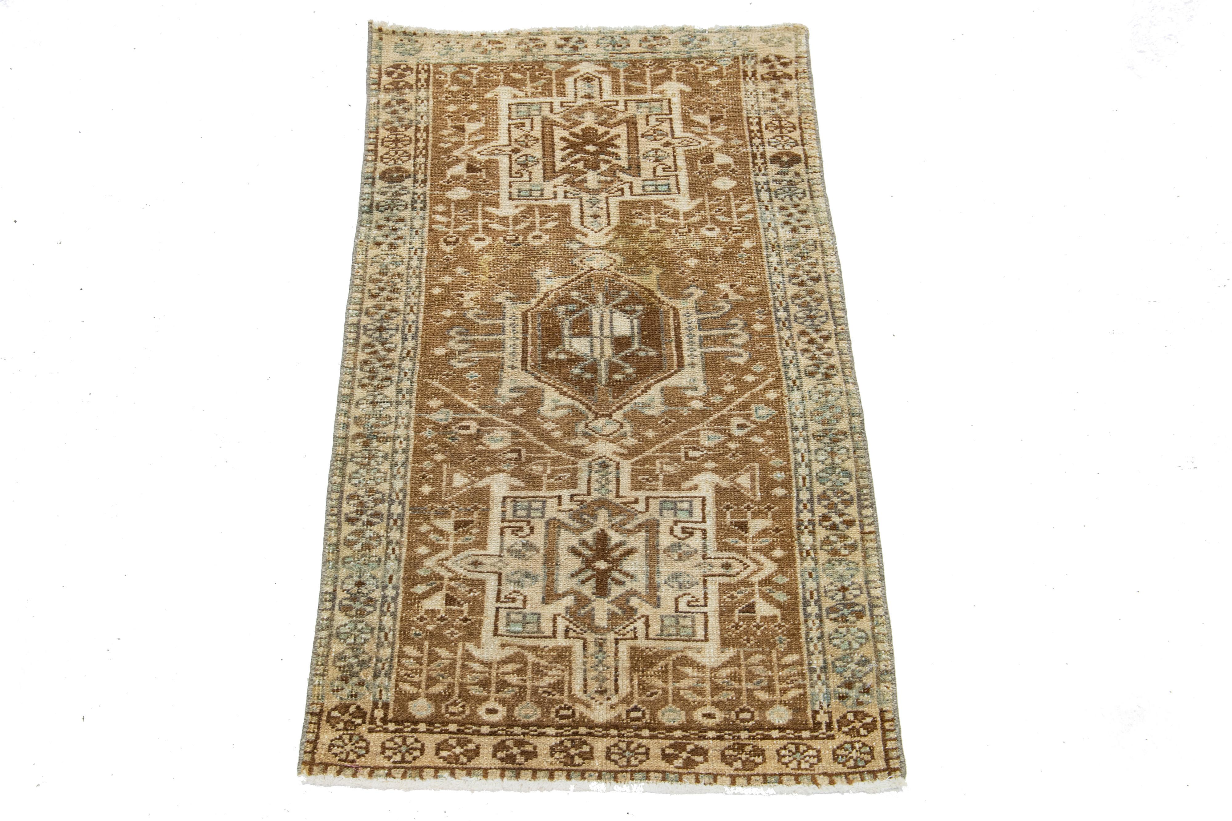 This Persian Heriz wool rug showcases an exquisite traditional floral medallion design with striking beige and blue accents against a brown background. 

This rug measures 2'1