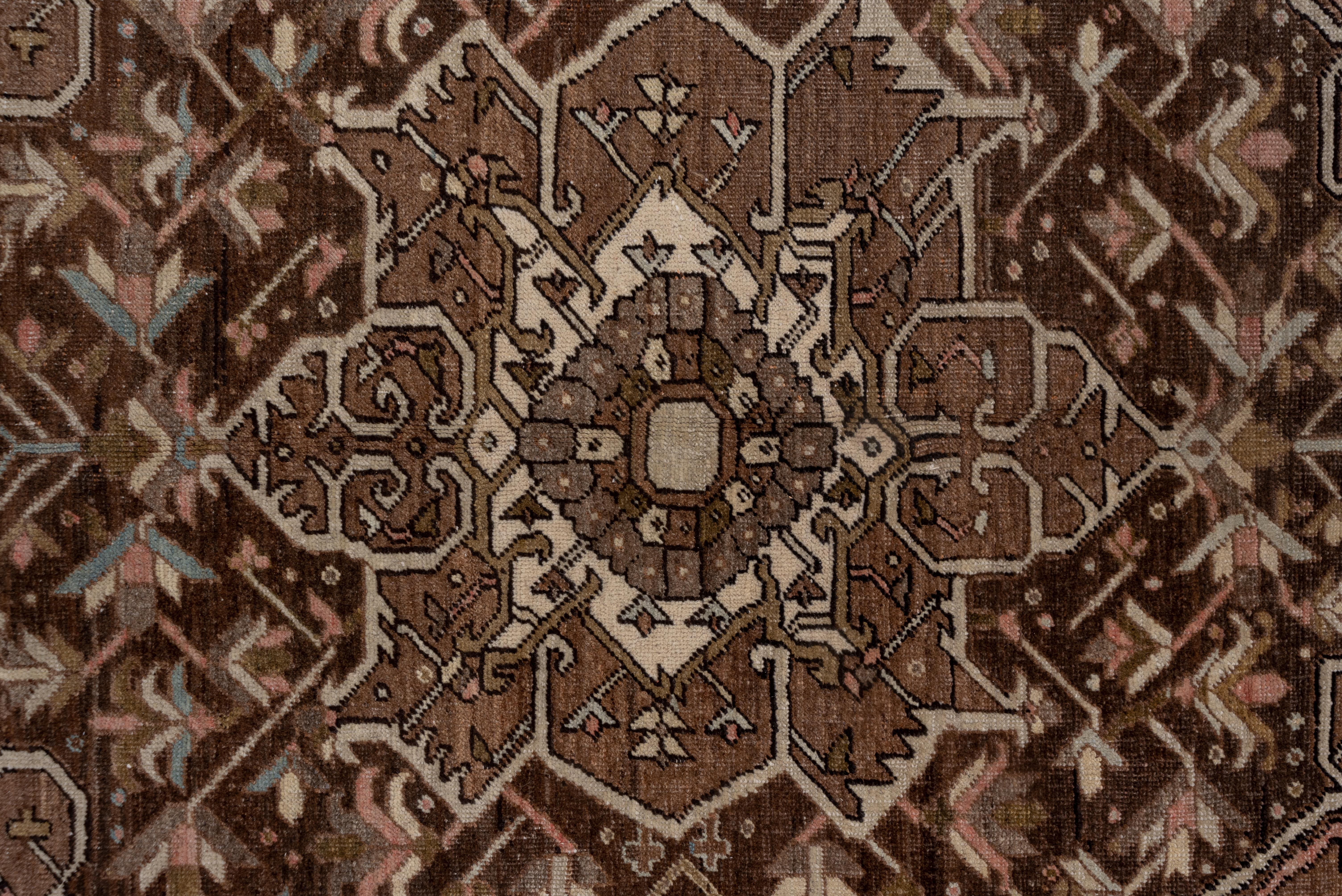This carpet has a bold brick oval medallion and four spearpoint pendants in the cardinal directions on a soft coral subfield, which, in turn, is set on a sand field with abstract palmette corner motives and long serrated, straight leaves. The