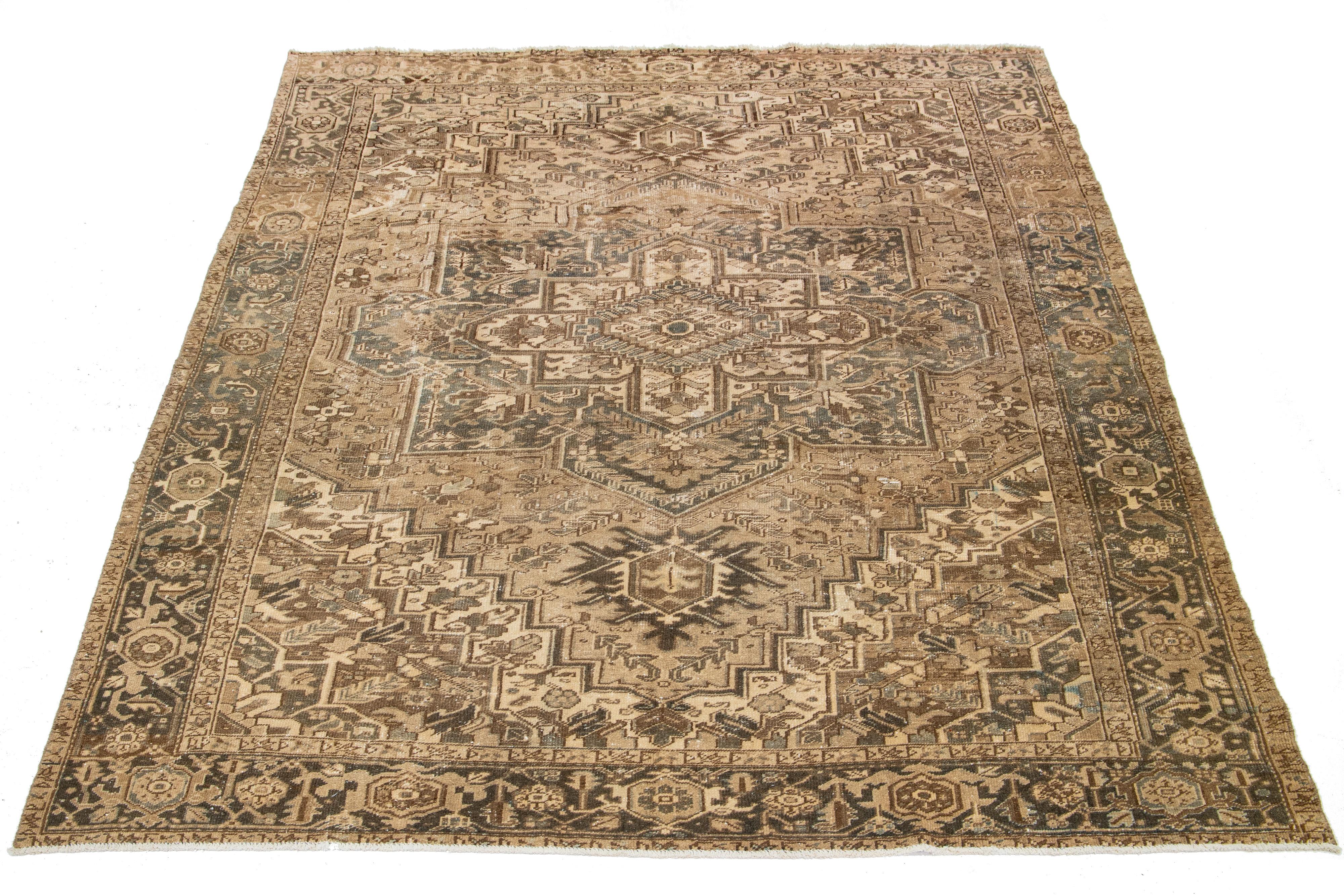 This Persian Heriz rug is handcrafted with wool that is knotted by hand. The field of the rug is adorned with a captivating design in a brown color, enhanced with beautiful shades of gray and beige.

This rug measures 9' x 11'8