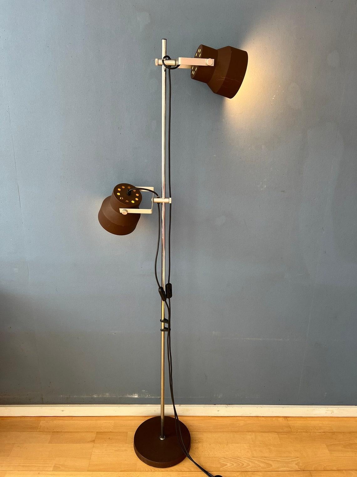 Brown mid century Anvia floor lamp with two adjustable shades. The two brown aluminium spots can be moved up and down the base and adjusted in any direction desirable. The lamp requires two E27/26 lightbulbs and currently has an EU-plug (directly