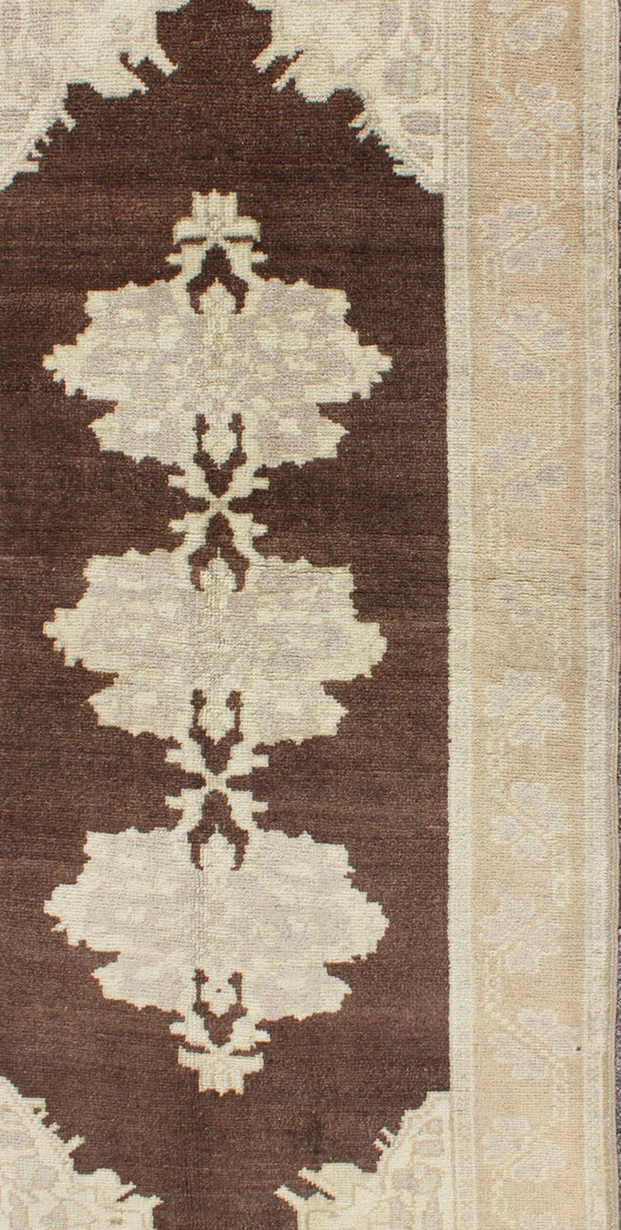 Brown background vintage Turkish Oushak runner with medallions in cream and ivory, rug en-604, country of origin / type: Turkey / Oushak, circa mid-20th century

This beautiful vintage Oushak runner from mid-20th century Turkey features a Classic