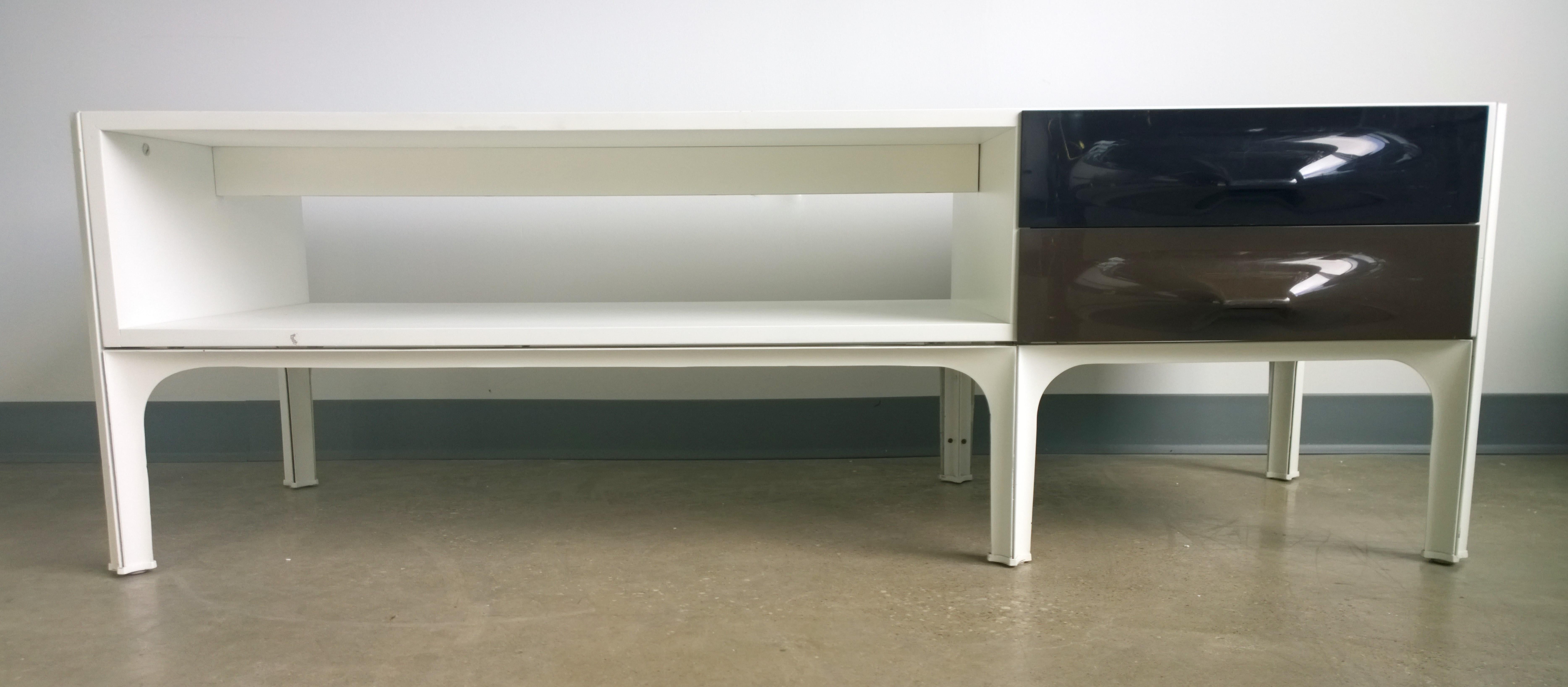 Offered is a Mid-Century Modern iconic Raymond Loewy white laminate low table / console / credenza / coffee table with two shelves and two signature black and chocolate brown molded plastic drawers that open from either side of the table. This table