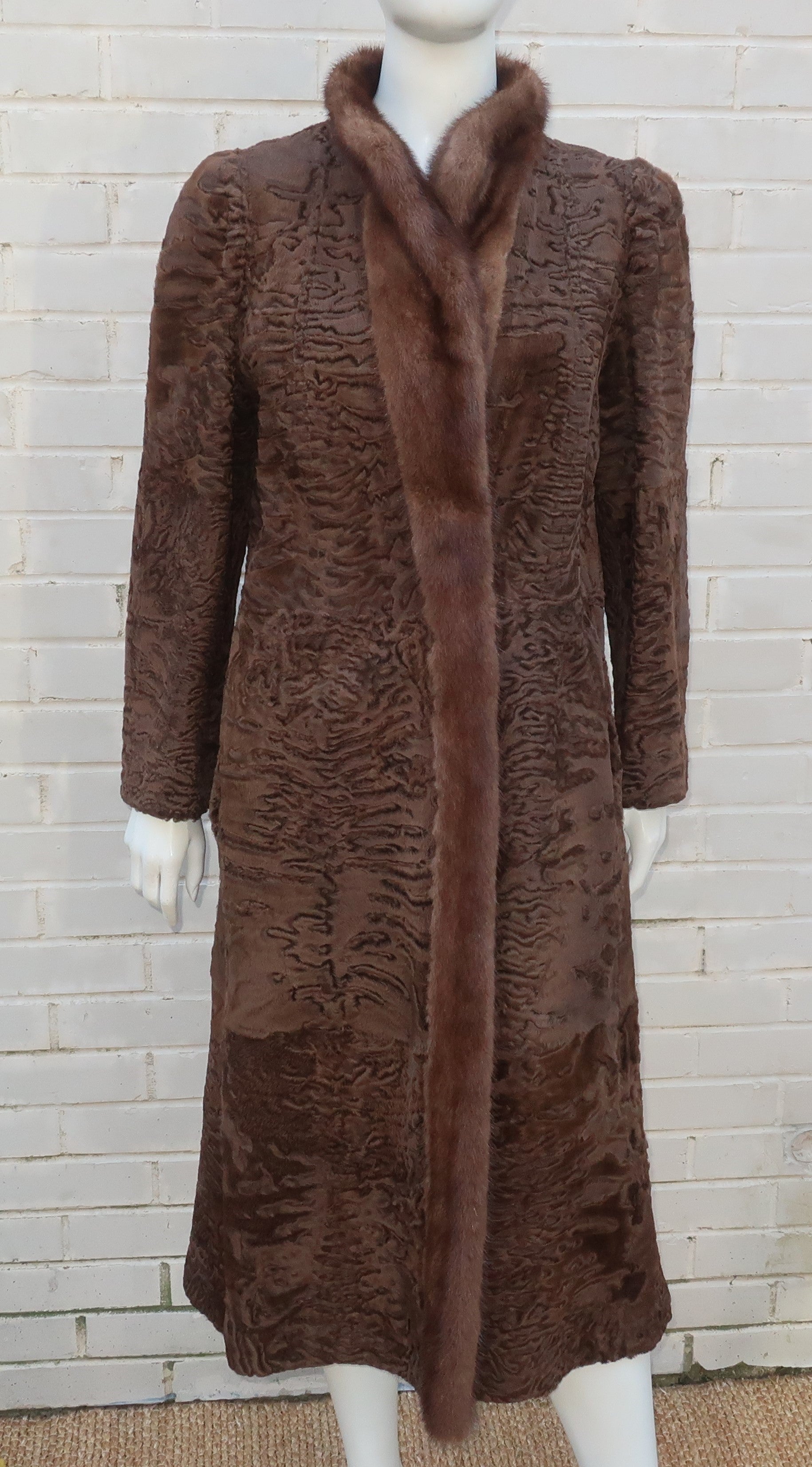 A strikingly handsome brown broadtail fur coat with mink trim which reverses to a more casual leather coat with a camel color suede grid.  The stylish 1970's design is by famed New York furrier, Christie Brothers, and has quality details.  The