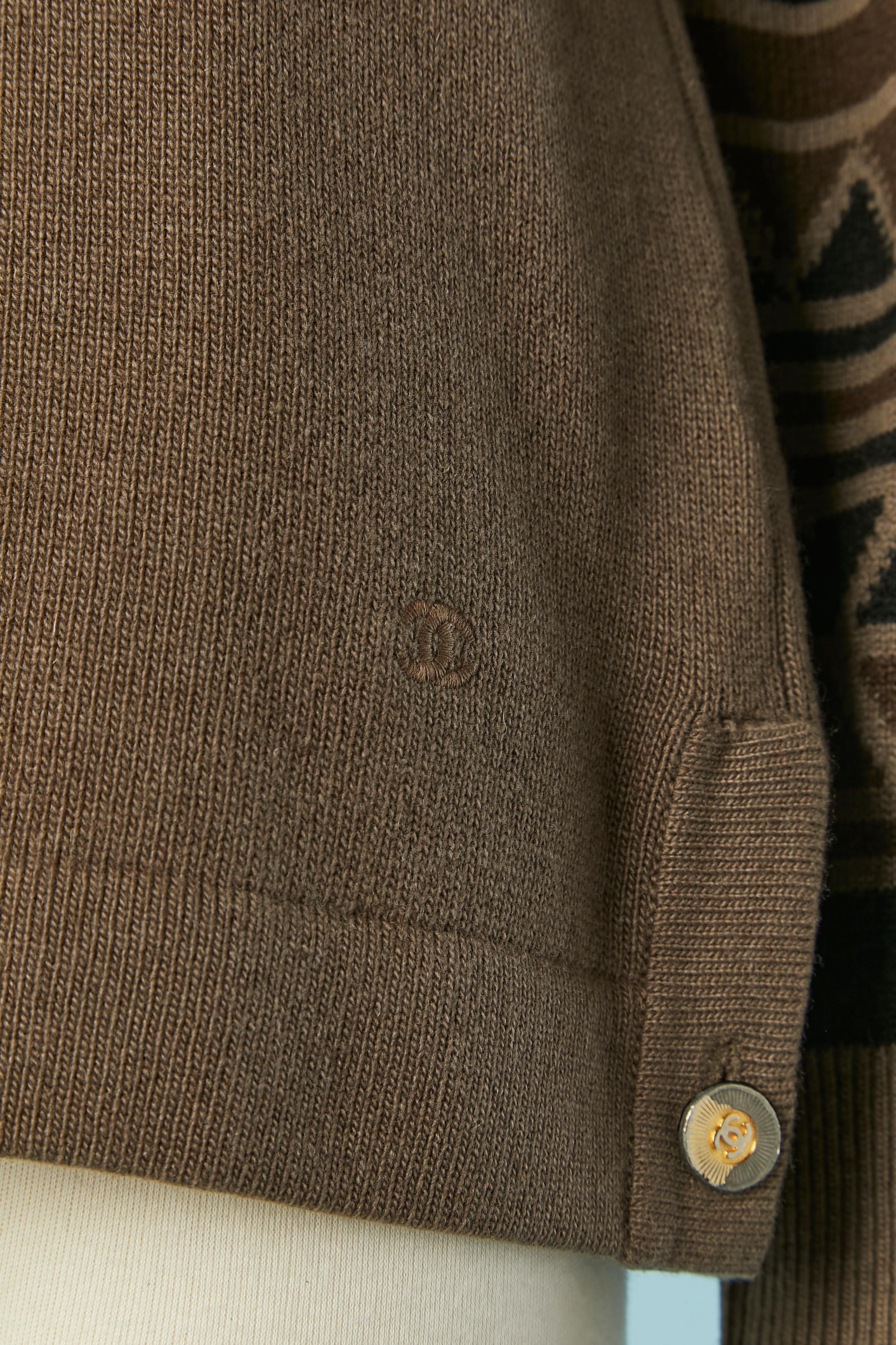 Pull en cachemire marron avec manches en jacquard. Fendu des deux côtés (longueur = 9cm) avec bouton de marque. Le vernis doré s'est décollé sur les boutons (voir les photos fournies). 
TAILLE 42 (Fr) L 