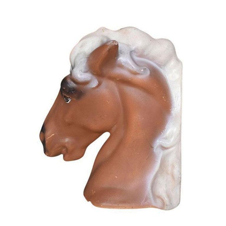 A large ceramic hand-painted horse head. This piece would be great in a nursery or for equestrians. Created from ceramic, this piece depicts the bust of a horse hand painted in brown, black, and cream. One side of the piece is flat and would be