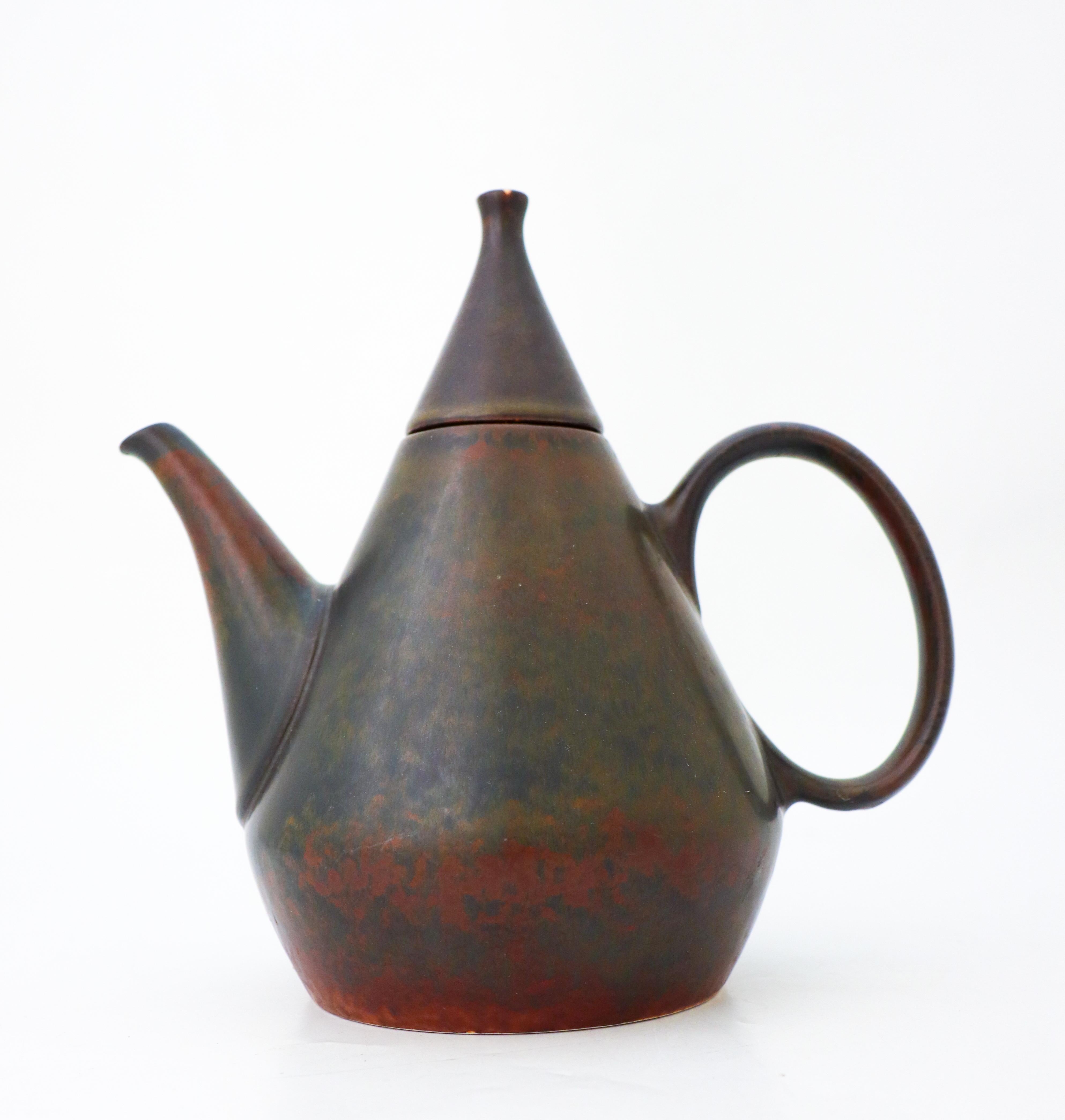 A brown teapot in ceramics with a lovely harfur glaze designed by Carl-Harry Stålhane at Rörstrand, Sweden in the 1950s. The teapot is 21,5 cm high and in excellent condition, it is marked as 2nd quality. The pot holds about one litre. 

Carl-Harry