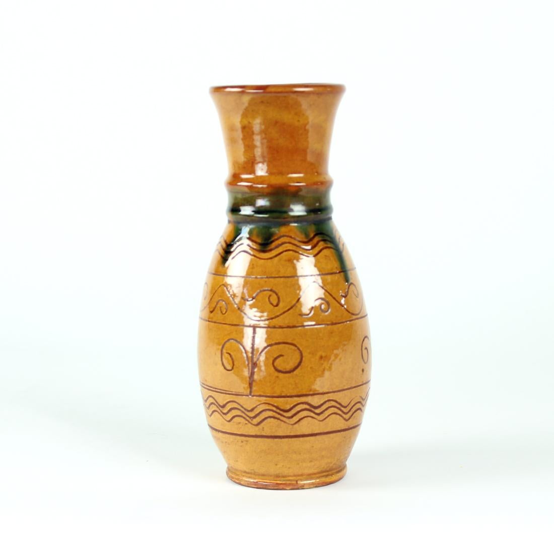 Beautiful vintage vase, made of ceramic with glazed finish. Interesting design and color combination. The vase is in a brown shade of color with a blue details on the neck of the vase. There are also folk art ornaments on the ceramic clay itself.