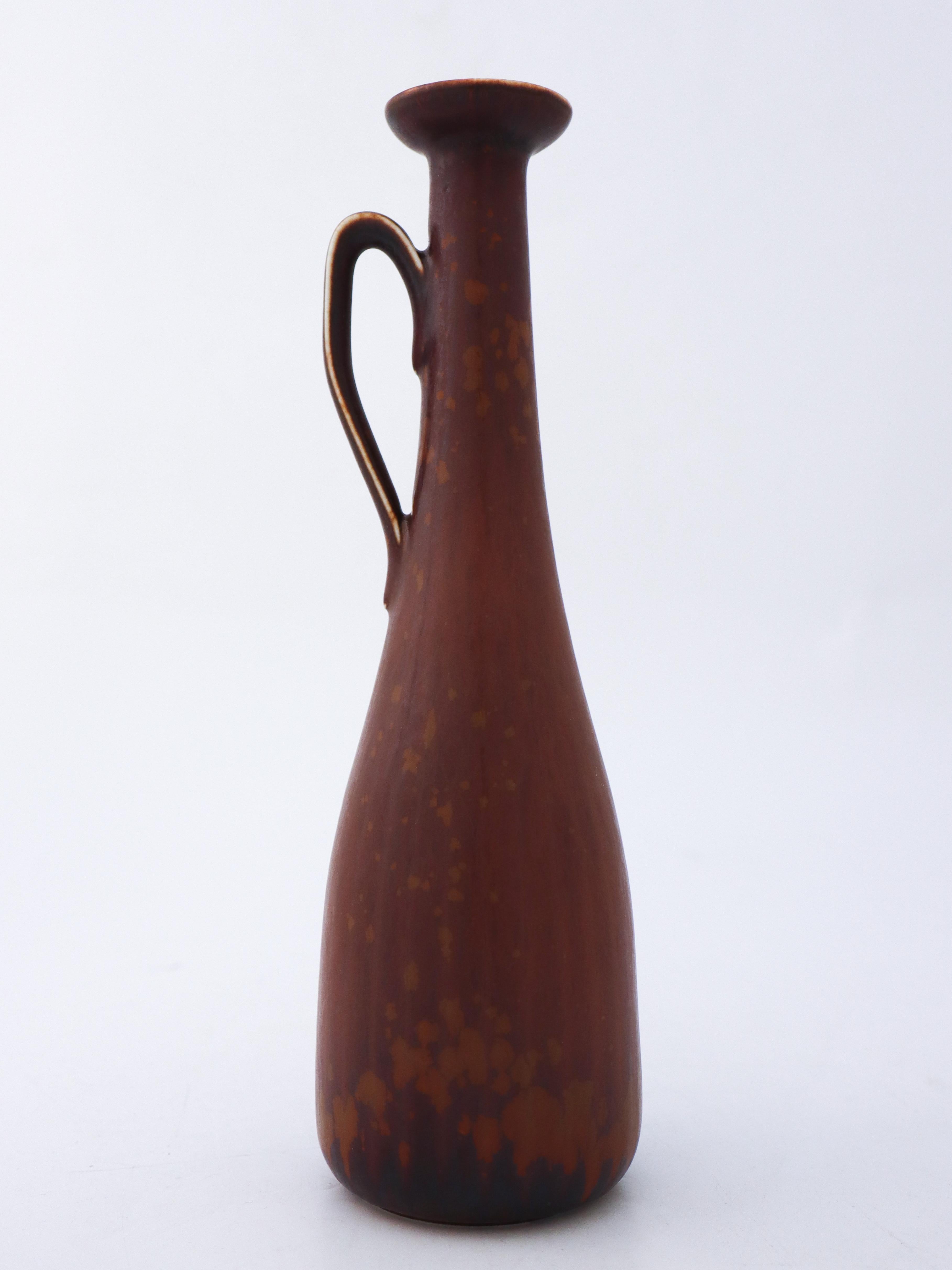 Die hübsche braune Vase wurde von Gunnar Nylund bei Rörstrand entworfen. Sie ist 24 cm hoch und hat einen Durchmesser von 6 cm. Es ist in neuwertigem Zustand und als 1. Qualität gekennzeichnet. 

Gunnar Nylund wurde 1904 in Paris geboren. Seine