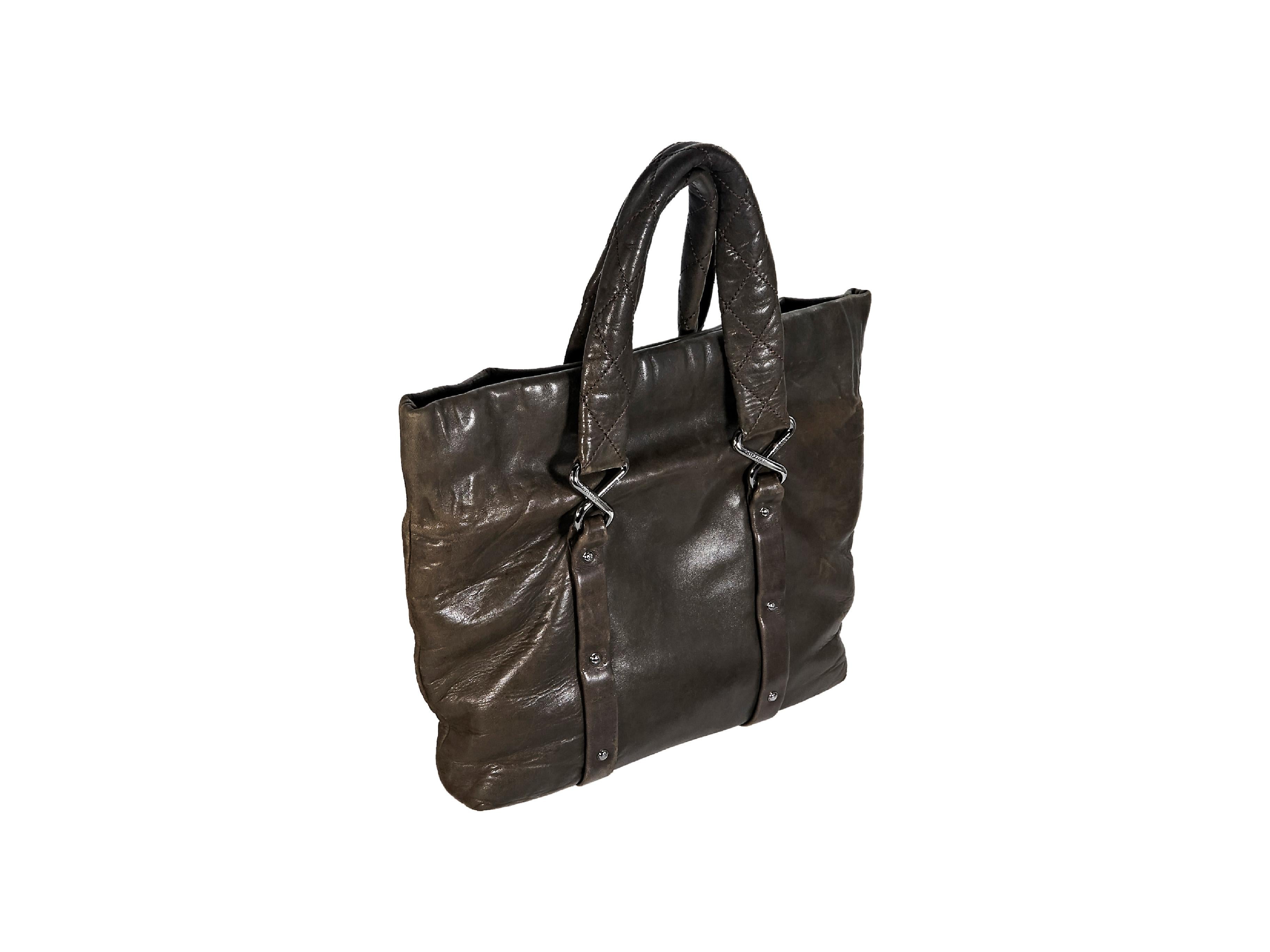 Product details:  Brown leather tote bag by Chanel.  Magnetic snap closure.  Top carry handles.  Lined interior with inner zip and slide pockets.  Front quilted twist-lock pocket.  Gunmetal-tone hardware.  16