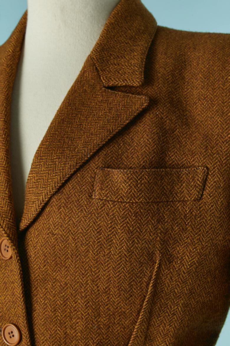 Veste à chevron marron à simple boutonnage. Doublure en acétate. Fermeture par boutons et boutonnières sur le milieu du devant et sur les poignets. Ceinture en cuir avec boucle CD. Pad d'épaule. 
TAILLE 38 (Fr) M 