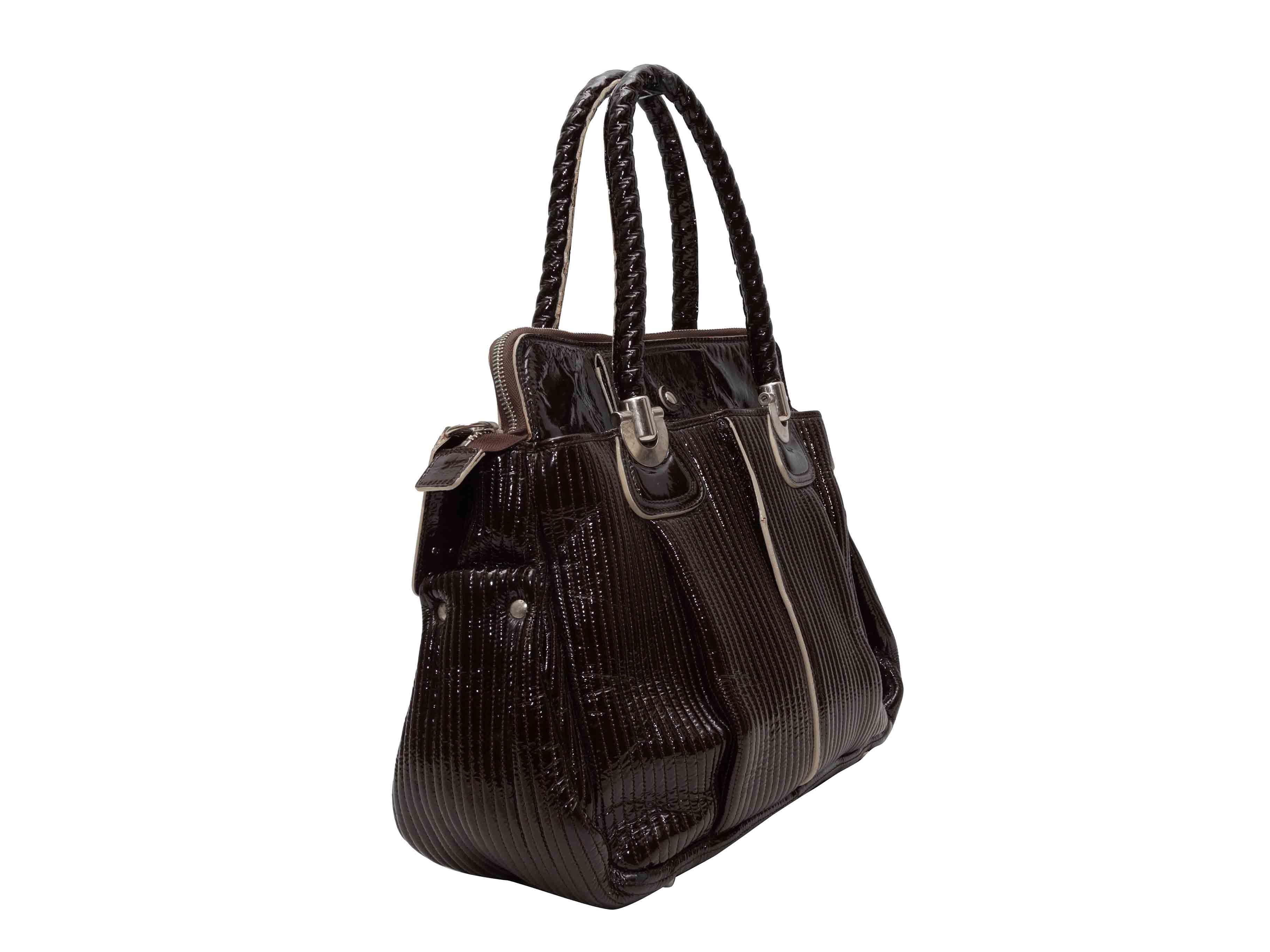 Borsa Heloise in vernice marrone di Chloe. La borsa Patent Heloise Tote è caratterizzata da un corpo in pelle verniciata, finiture in argento, doppio manico arrotolato e chiusura con zip. 17