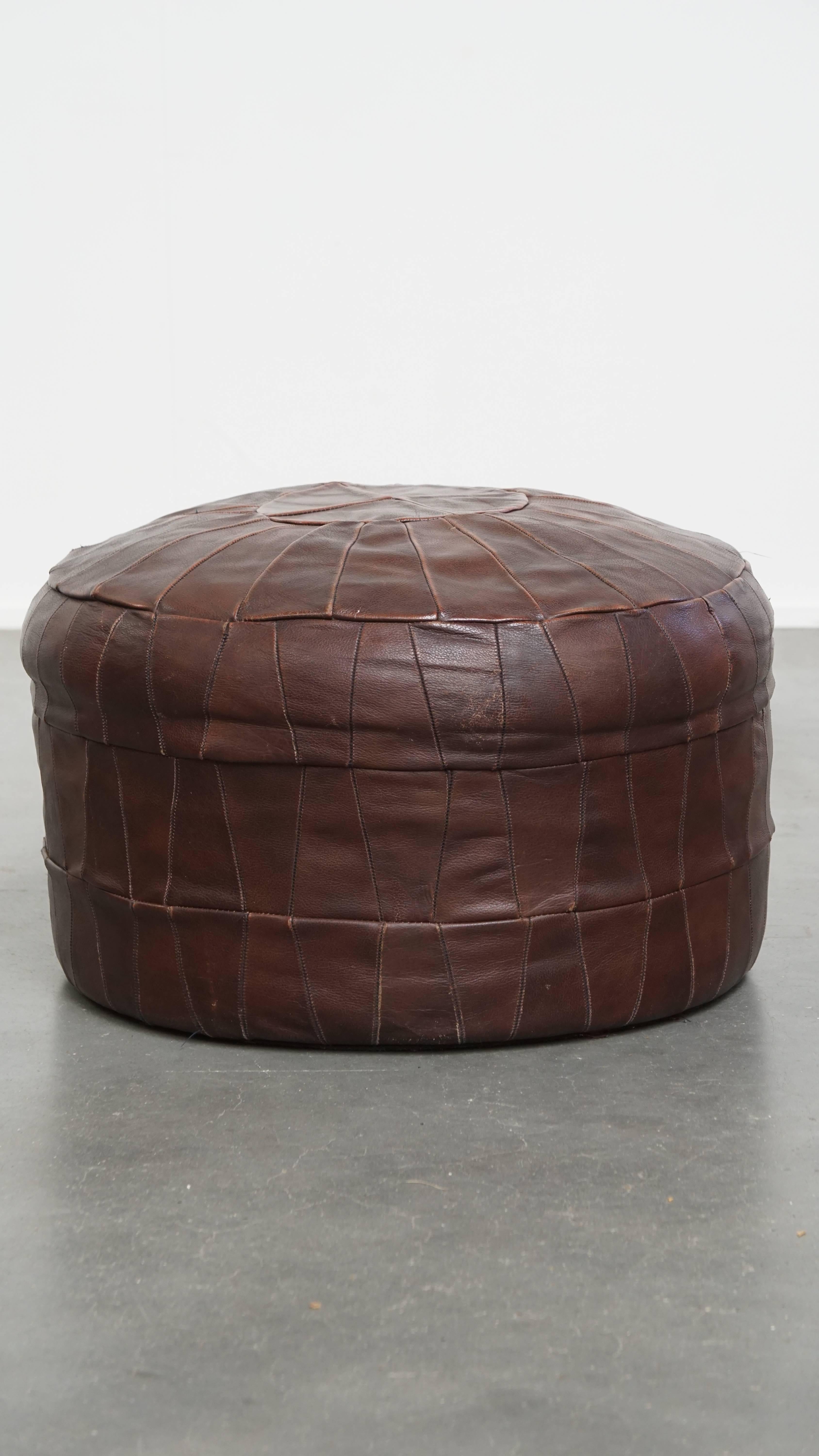 Offered here is this brown cowhide vintage patchwork design pouf from the 1970s. A cowhide footstool, also known as an ottoman, turns your already comfortable armchair into a true relaxation haven. With your feet resting on this ottoman, you can