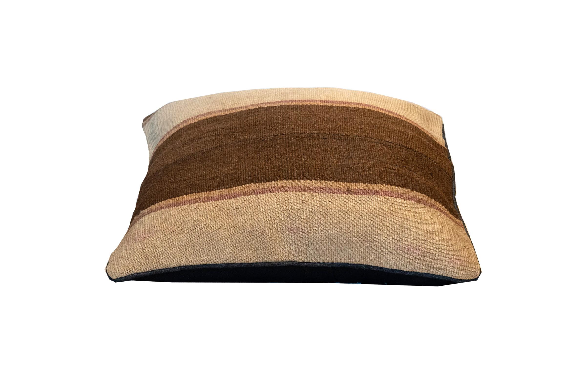 This simple stripe cushion has been woven by hand using traditional kilim weaving techniques with hand-spun wool. Featuring a simple stripe design, with thick cream and brown lines, with smaller beige and subtle pink lines. With some small signs of