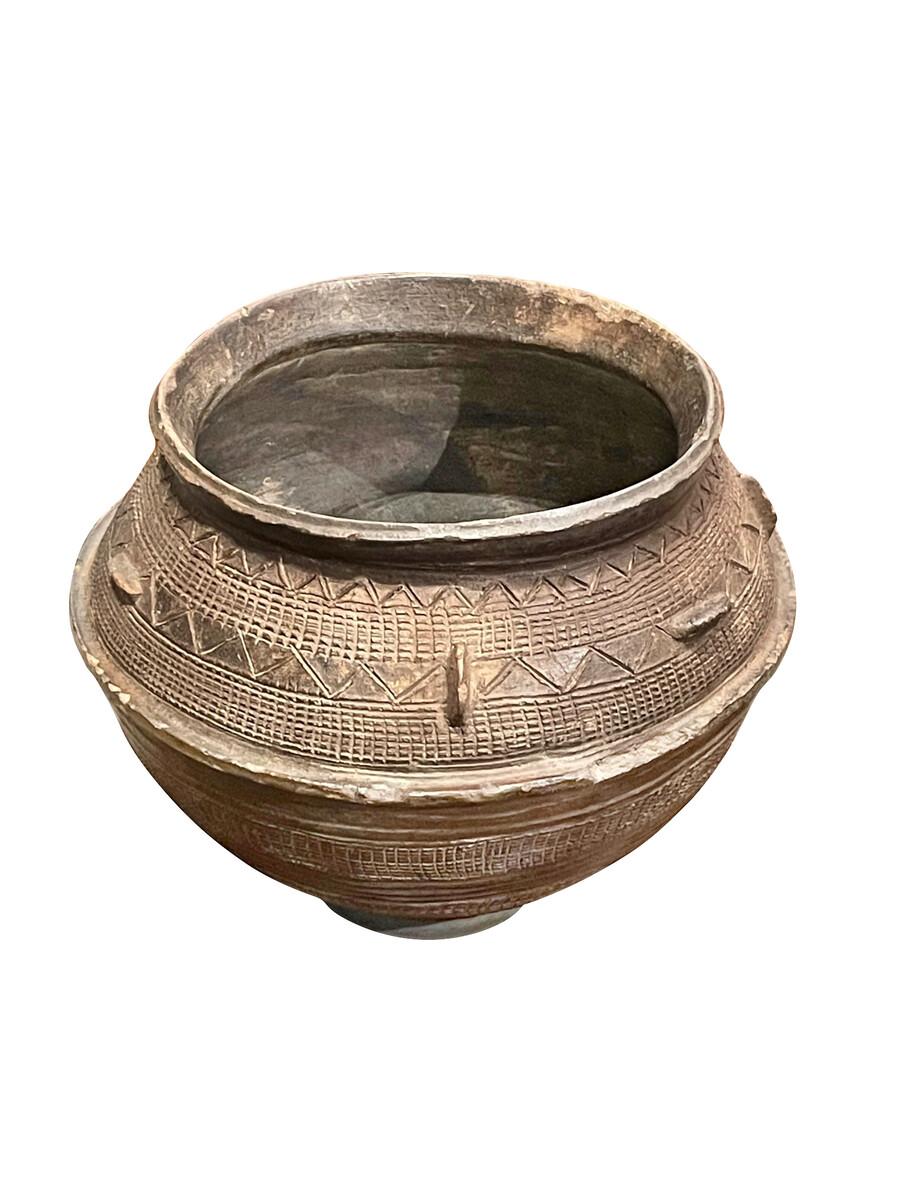 1950s Ethiopian terracotta large water vessel with decorative design.
Hand carvings create a three dimensional texture.
Six small flat handles are arranged vertically and horizontally around the vase.
The vessel has a round bottom and sits on a