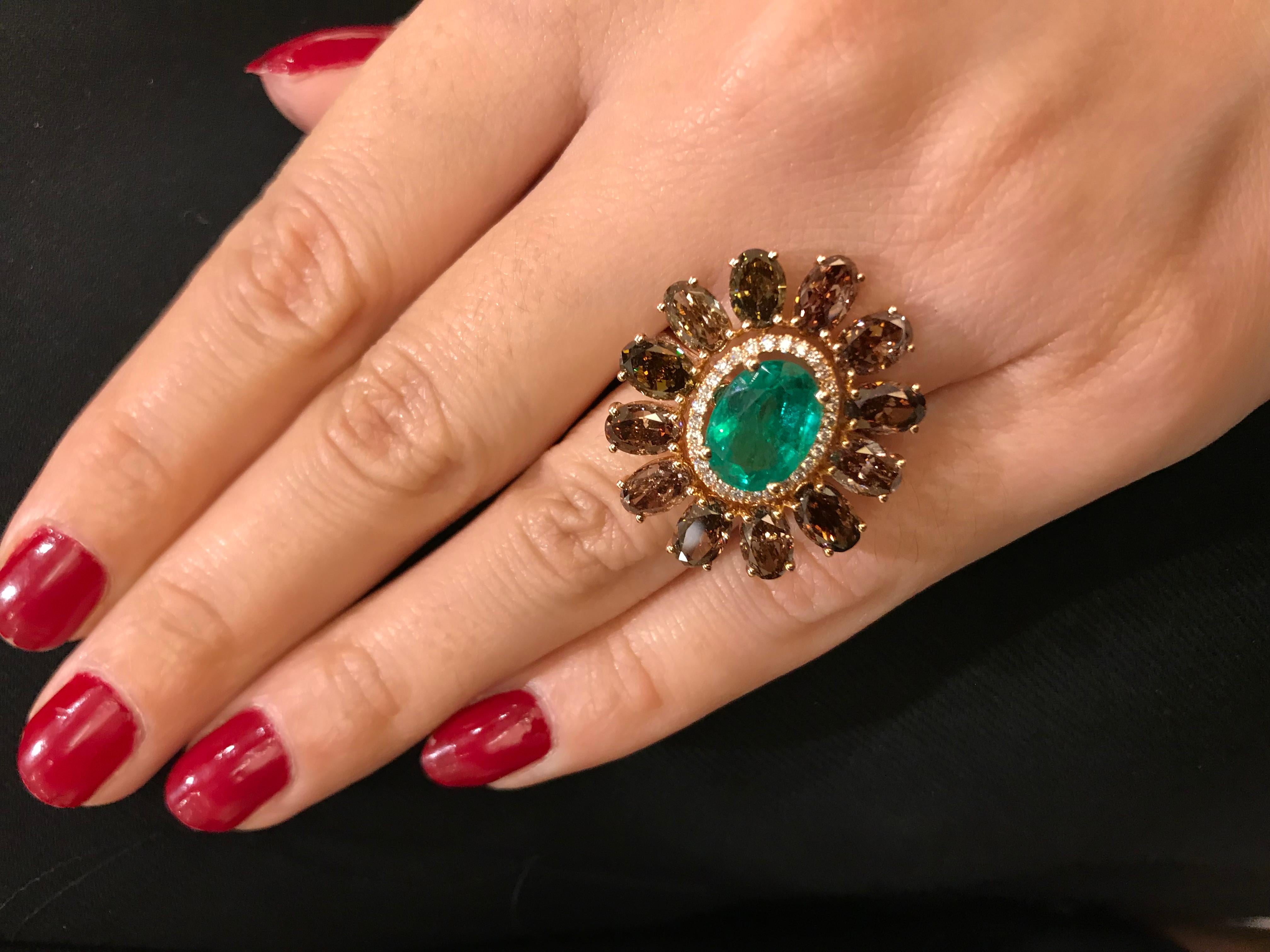 Inspired by the evening sun in the fall season this handcrafted 18K rose gold cocktail ring features an oval emerald accented by round brilliant diamonds in the center and is surrounded by 12 oval brown diamonds weighing approximately 0.60 carats
