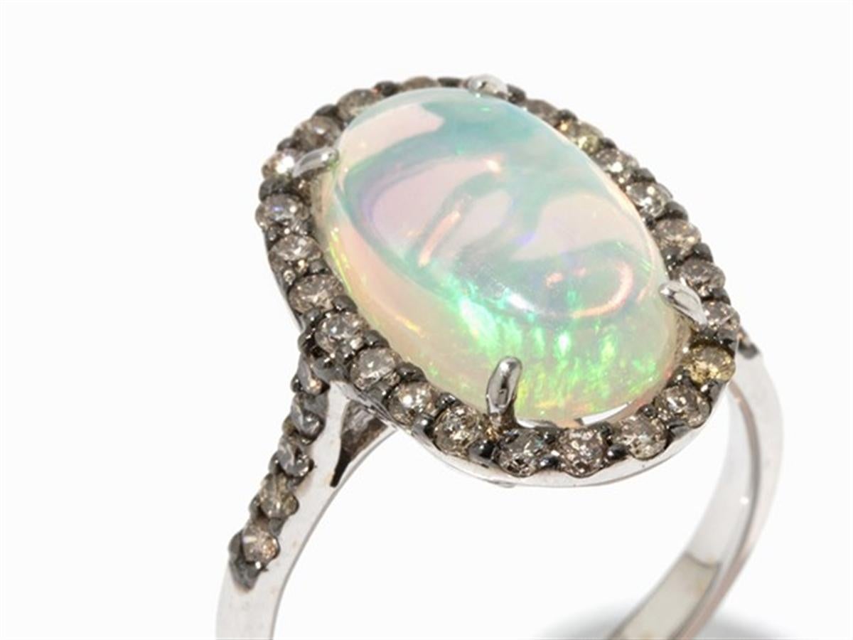 - 750 white gold
- Punched with the fineness
- 1 Crystal Opal cabochon, approx. 3.15 ct (approx. 15 x 8.7 mm)
- 34 brilliant-cut diamonds, total approx. 0.5 ct, in brown colour
- Ring size: 53; US 6,4
- Weight: approx. 4.2 g

Beschreibung
·	750