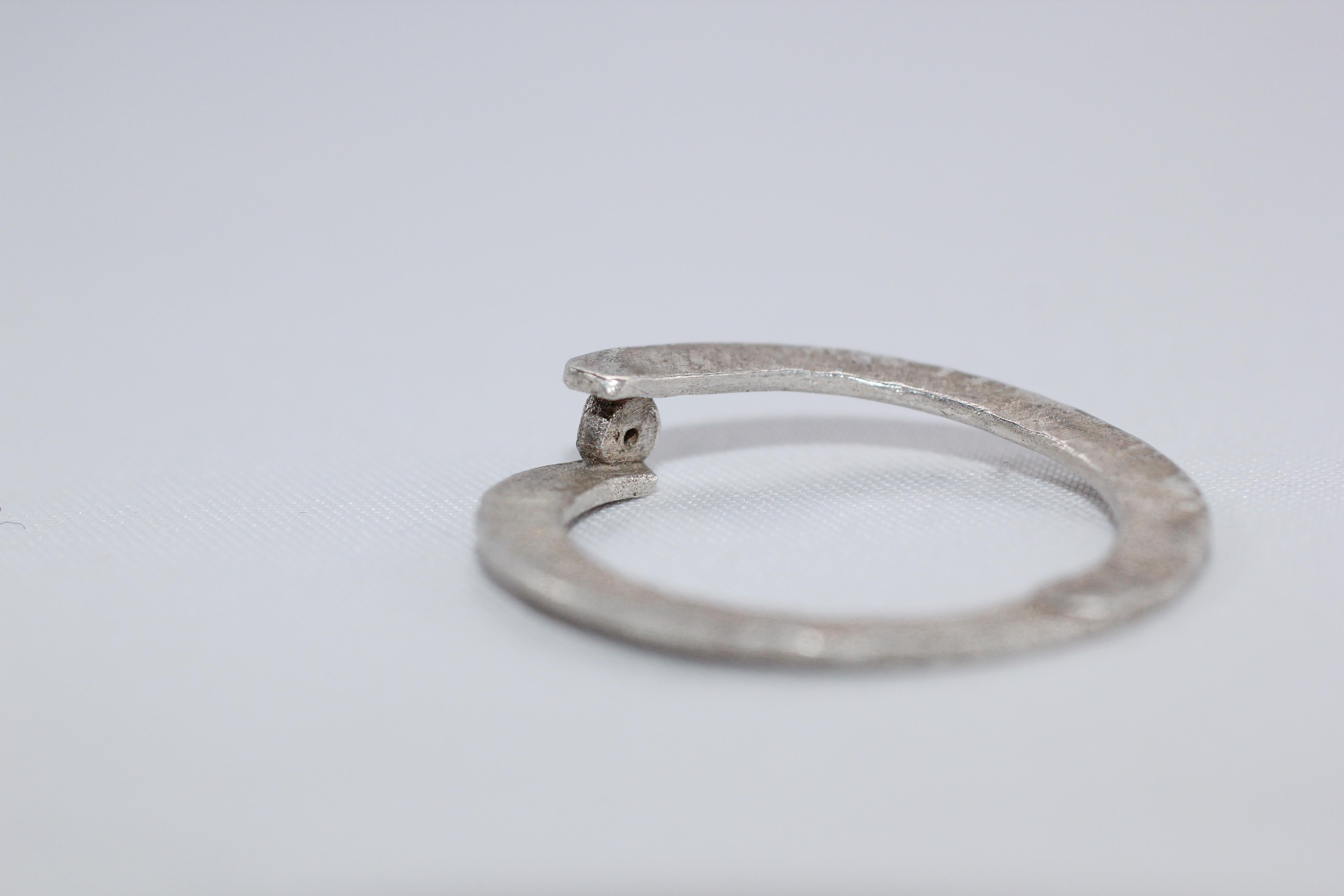 Simplicity With A Twist in sterling silver holding a brown diamond. Modern stackable fashion ring. 

This striking ring is first hand forged in 21k gold, then cast in various metals and a hammered/satin finish is added. Wear it alone or combine with