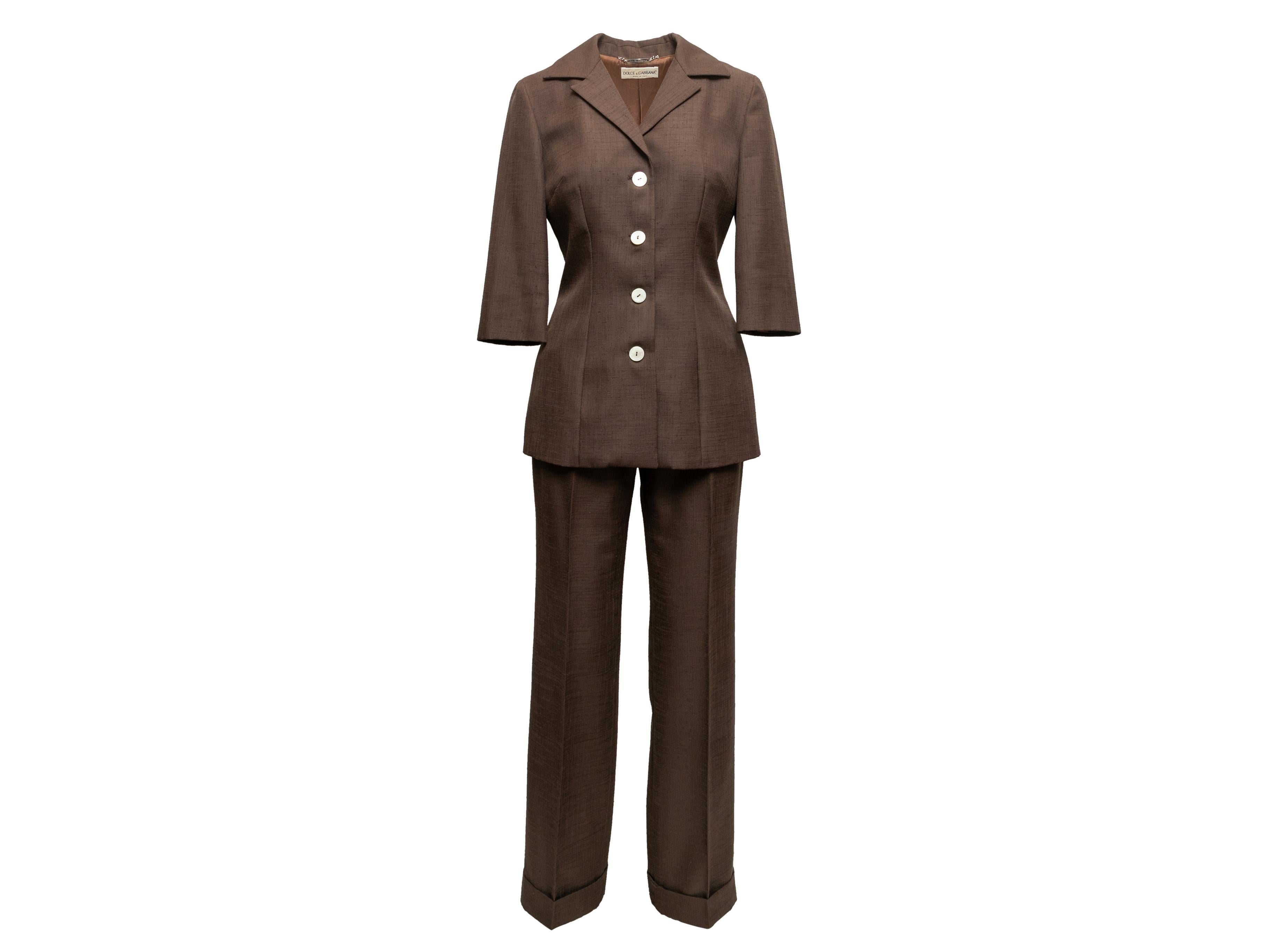 Brown pant suit by Dolce & Gabbana. Blazer features notched lapel, three-quarter sleeves, and front button closures. Pants feature dual hip pockets and front zip closure. Blazer- 38