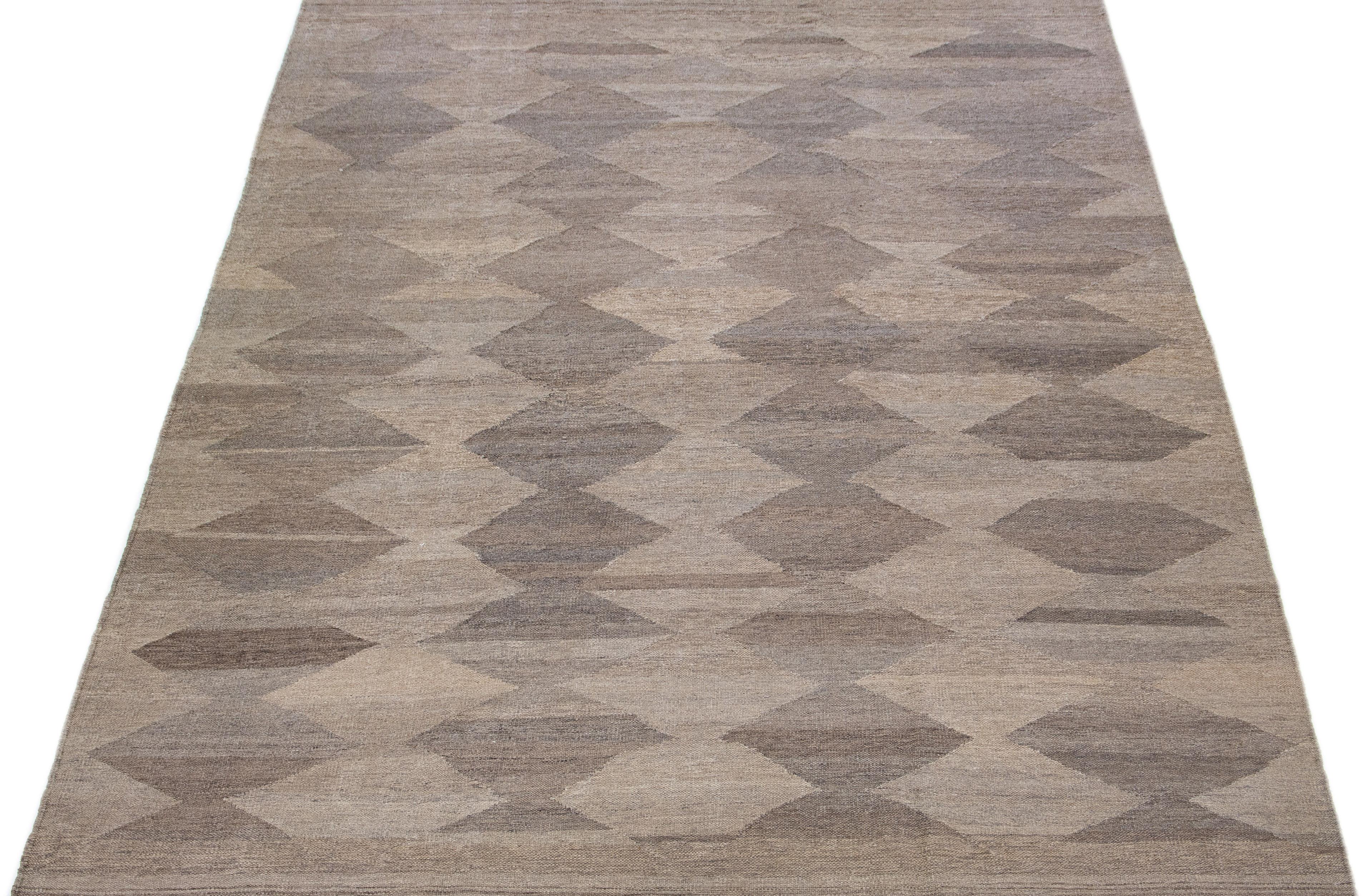 This wool flatweave Kilim rug is enhanced with a captivating brown color field and grey highlights throughout. Its geometric design gives it a modern, aesthetically-appealing allure.

This rug measures 8'8