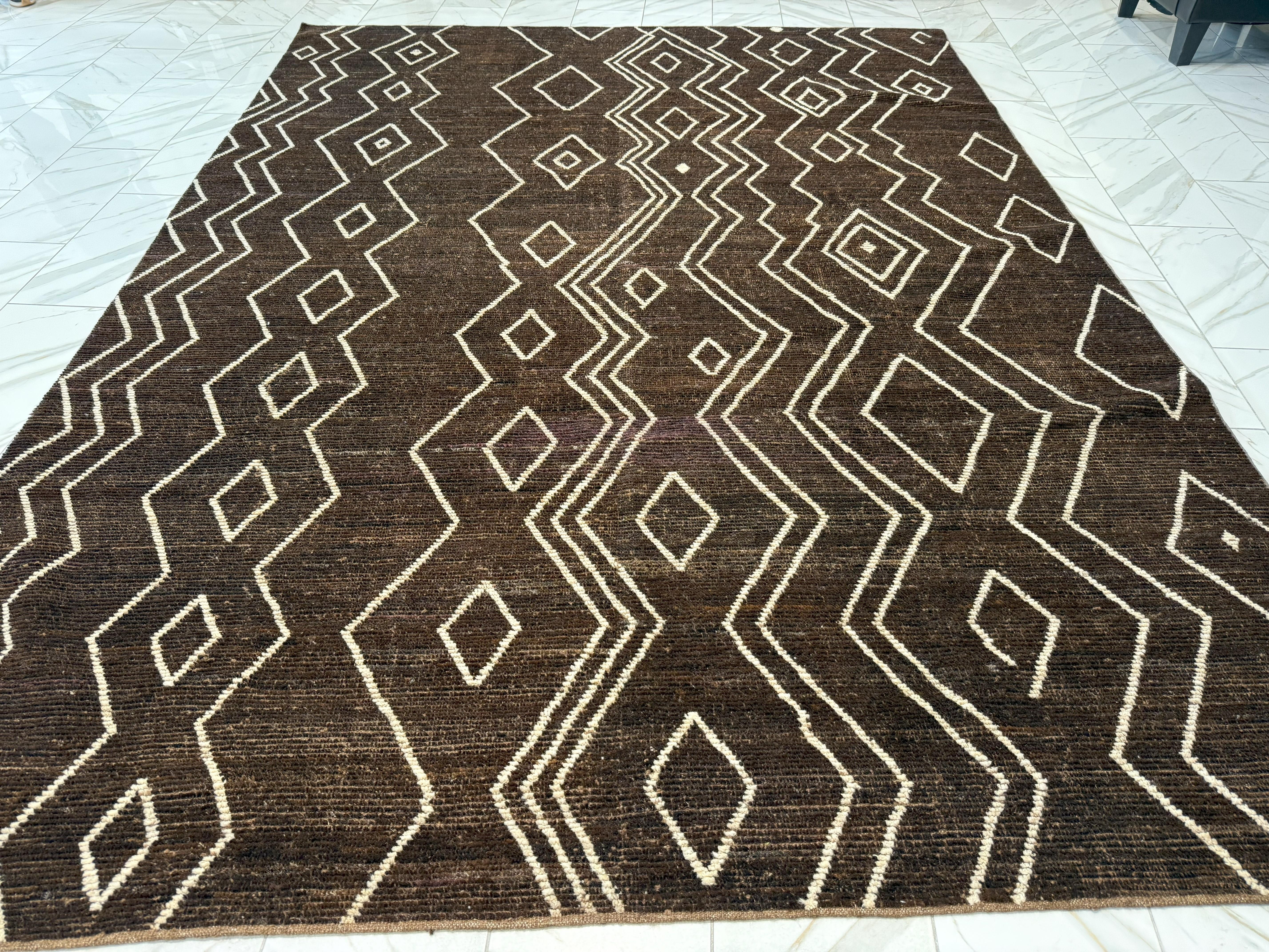 Coming from our newest collection of Moroccan G designs, this brown geometric Moroccan design area rug is handmade and hand-knotted made in Pakistan. It has a cotton base and is made from all goat wool yarns. It features a textured feel that