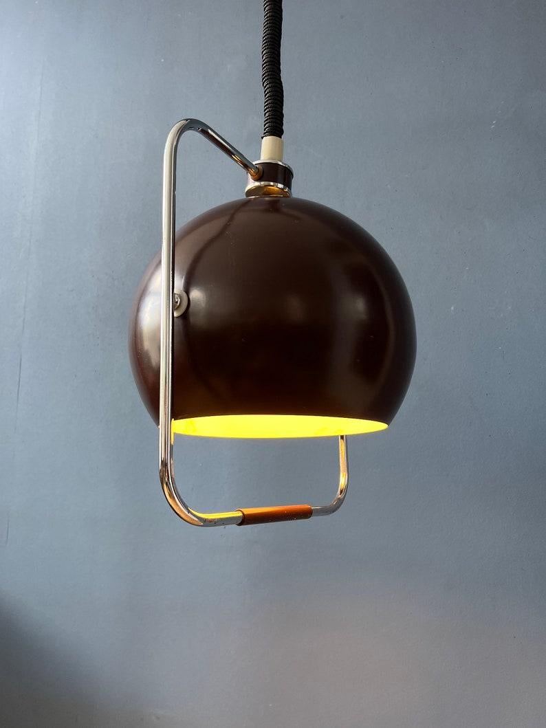 Lampada a sospensione dell'era spaziale GEPO di metà secolo con paralume marrone a forma di bulbo oculare. Questa lampada giocosa può ruotare il paralume intorno al suo asse. La lampada è realizzata in metallo e alluminio. La lampada ha un attacco