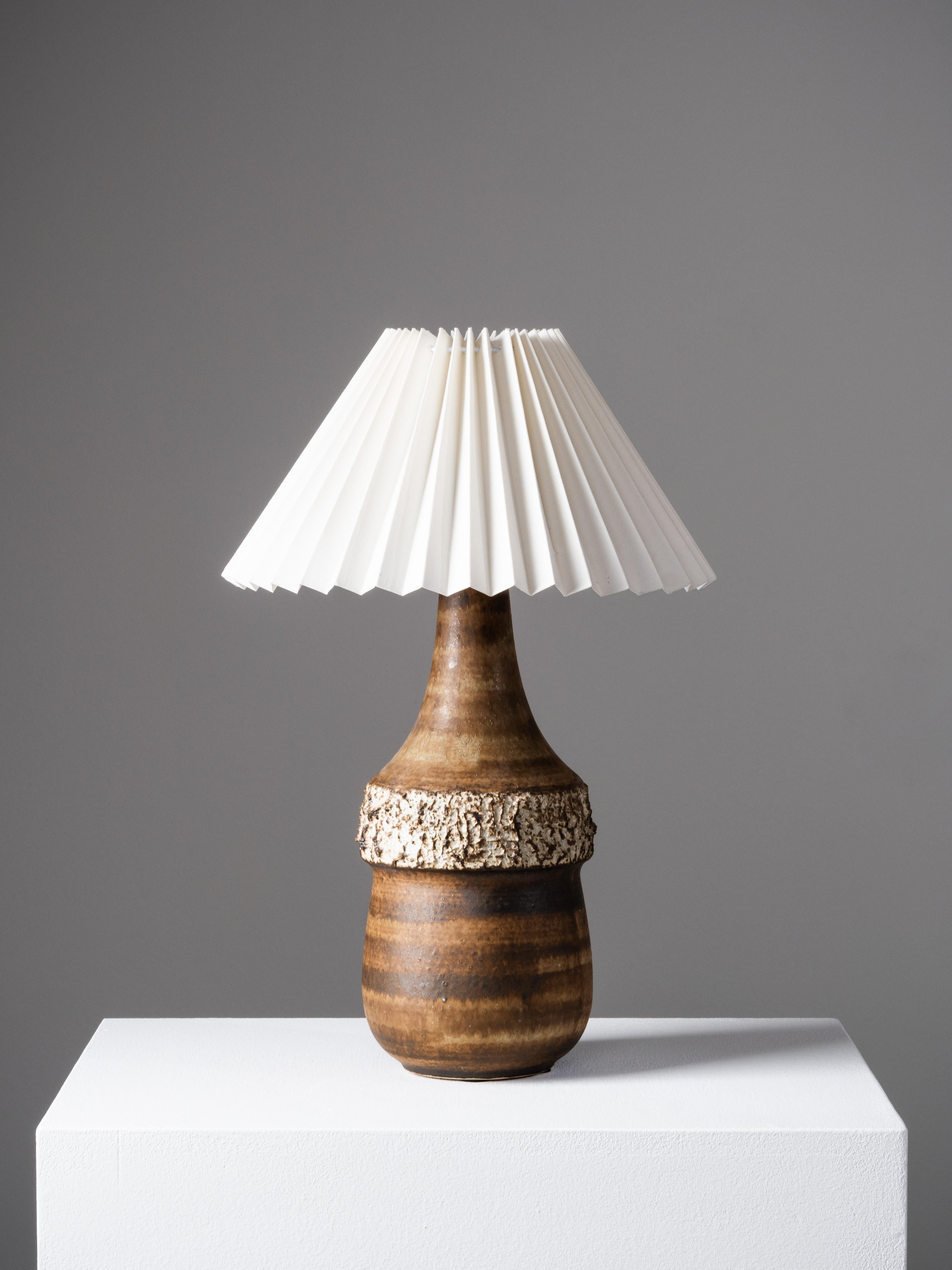 A beautifully sculptural stoneware table lamp by Bruno Karlsson, produced by the Swedish ceramics workshop Ego Stengods in the 1960s. The lamp features a richly textured form with a striking contrast between the smooth, gently tapered upper body and