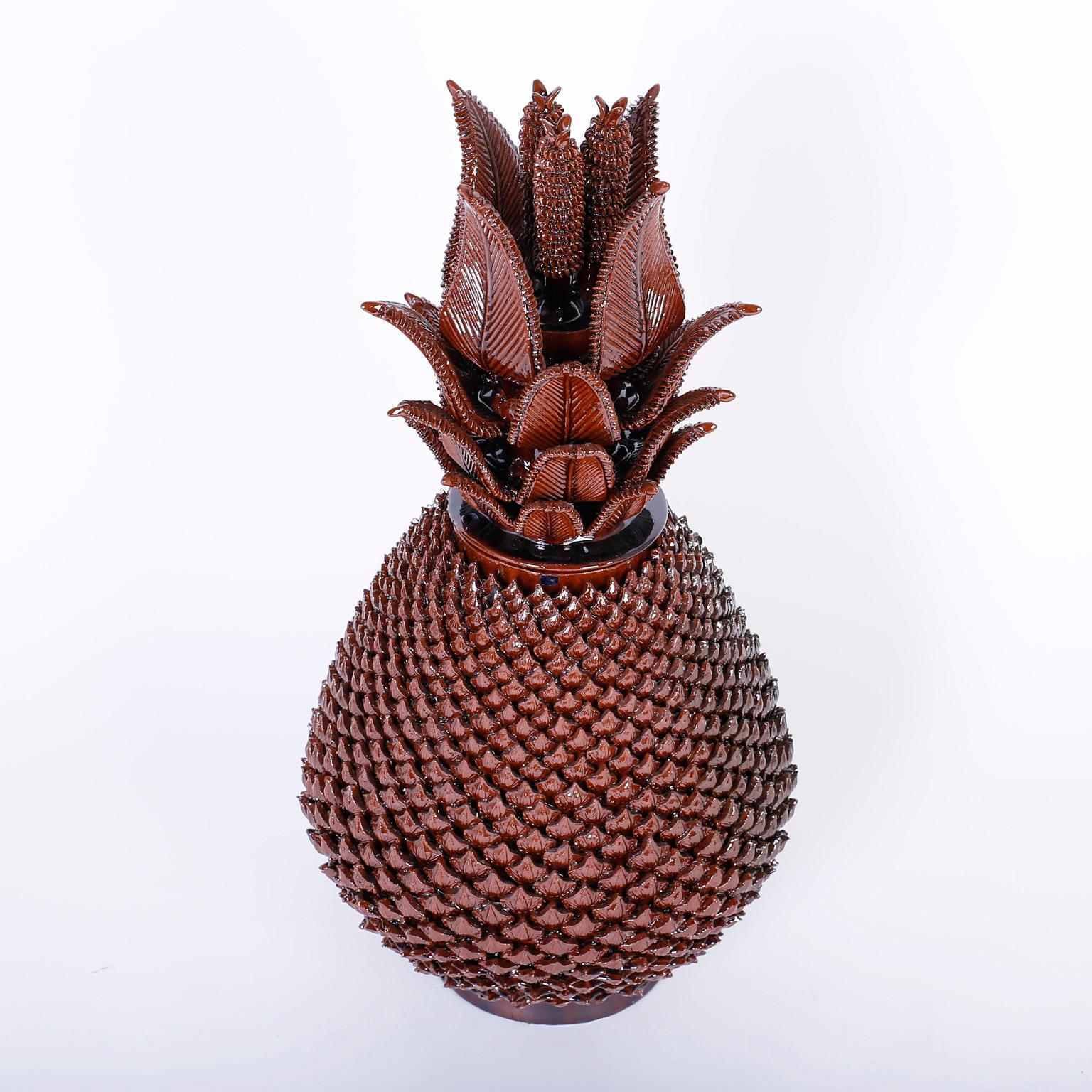 Brown glazed terracotta lidded pineapple urn with an impressive display of pottery prowess, featuring a dramatic leaf and cone lid over an ambitious repeating husk pattern on the jar.