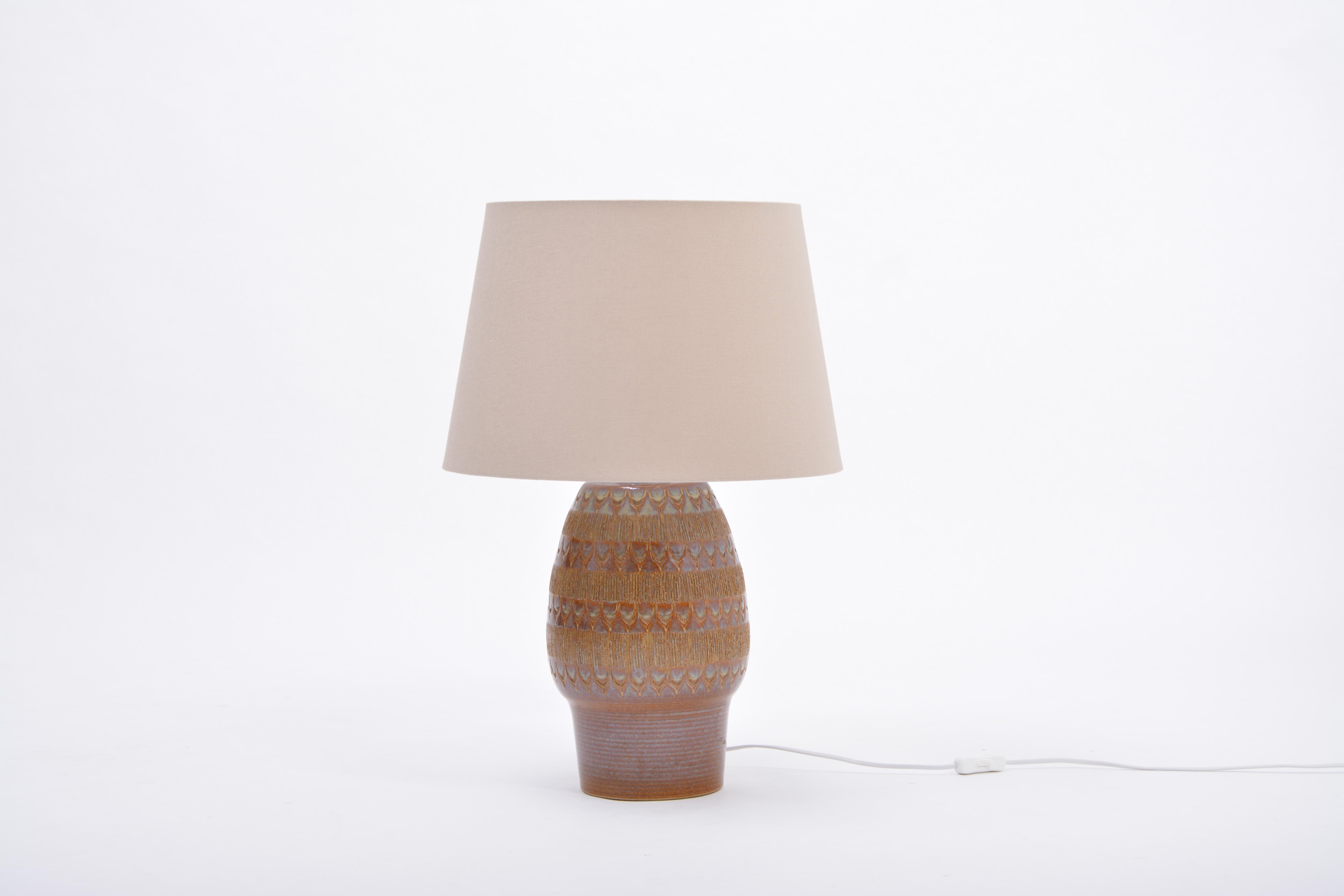 Brown handmade Mid-Century Modern Danish stoneware table lamp by Soholm Stentoj

Spectacular tall table lamp made of stoneware with ceramic glazing in various tones of blue. The base of the lamp features various graphic patterns. Handmade in