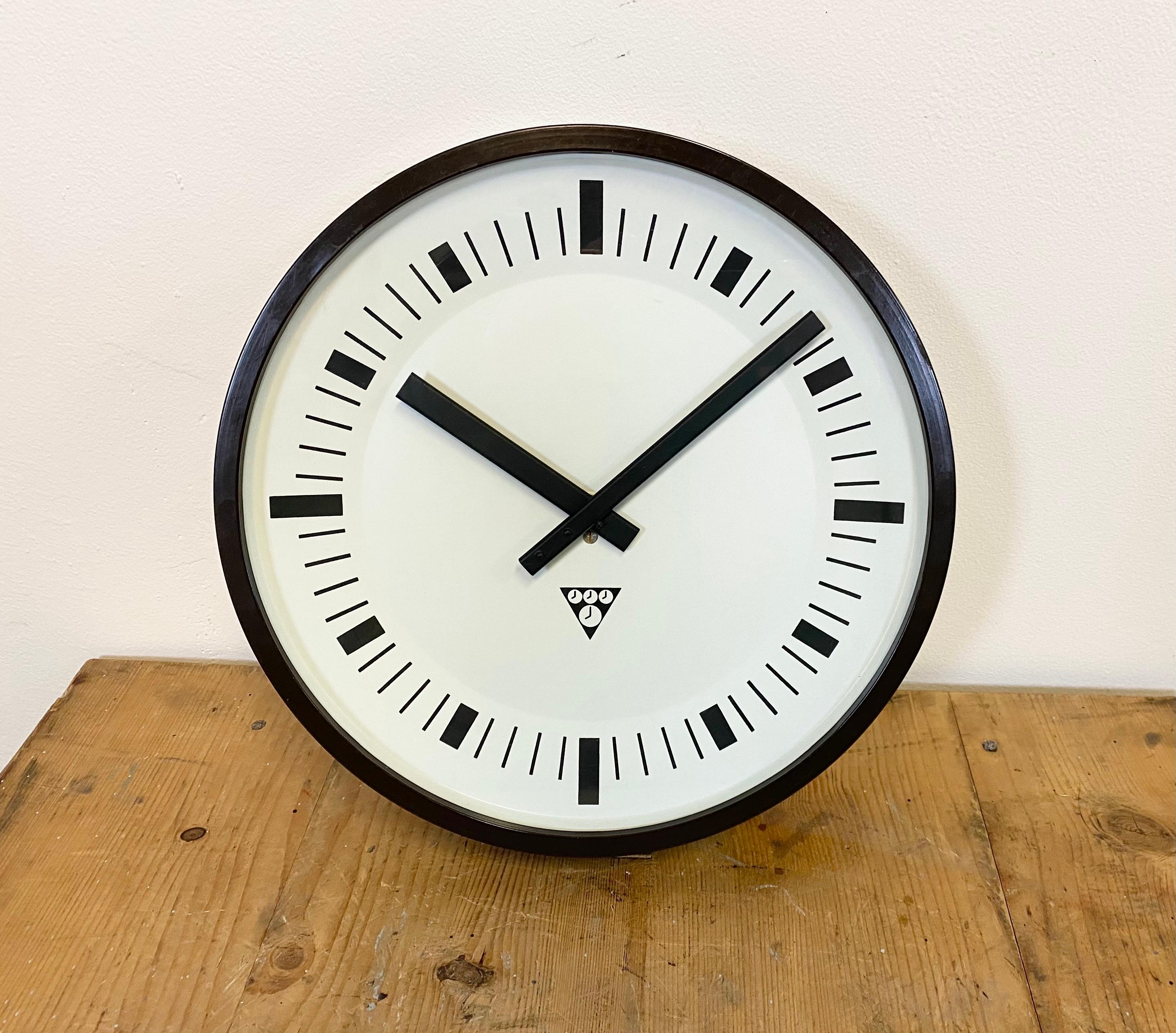 This wall clock was designed by Pragotron in former Czechoslovakia during the 1970s. The piece features a brown bakelite frame, aluminium dial and clear glass cover. The piece has been converted into a battery-powered clockwork and requires only one