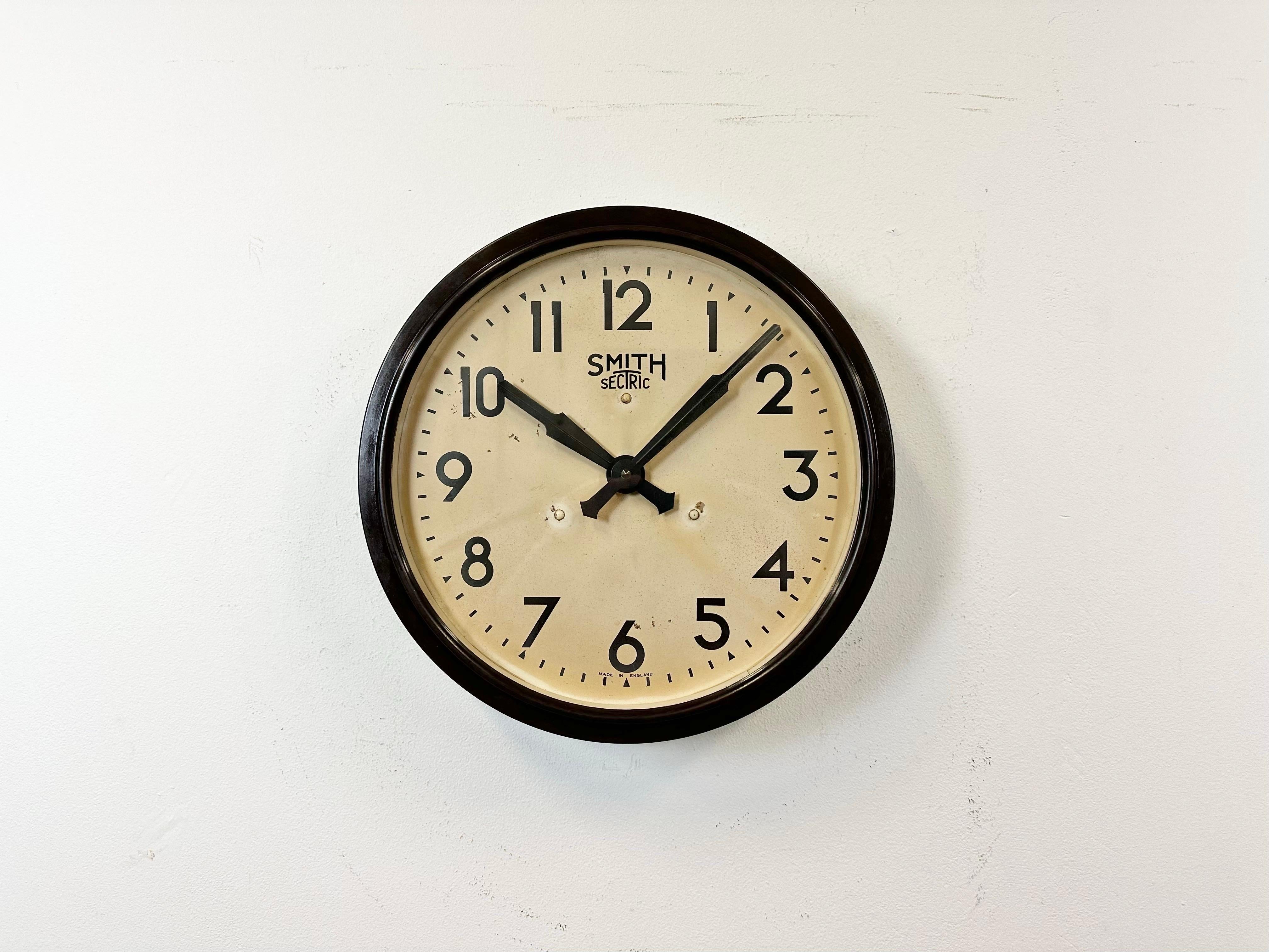 Cette horloge murale a été produite par Smith Sectric en Angleterre dans les années 1950. Elle présente un cadre en bakélite brune, un cadran en fer, des aiguilles en aluminium et un couvercle en verre transparent. La pièce a été convertie en un