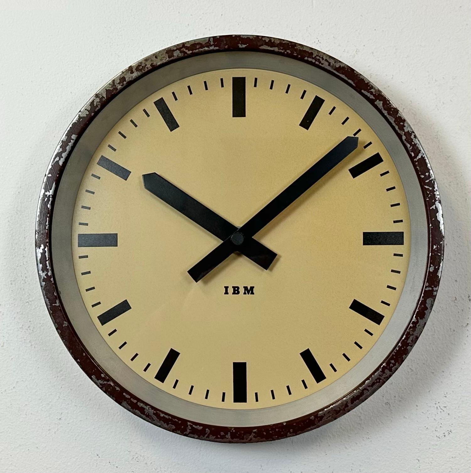 This wall clock was produced by IBM in USA during the 1950s. It features a brown metal frame, iron dial, aluminium hands and a clear glass cover. The piece has been converted into a battery-powered clockwork and requires only one AA-battery. The