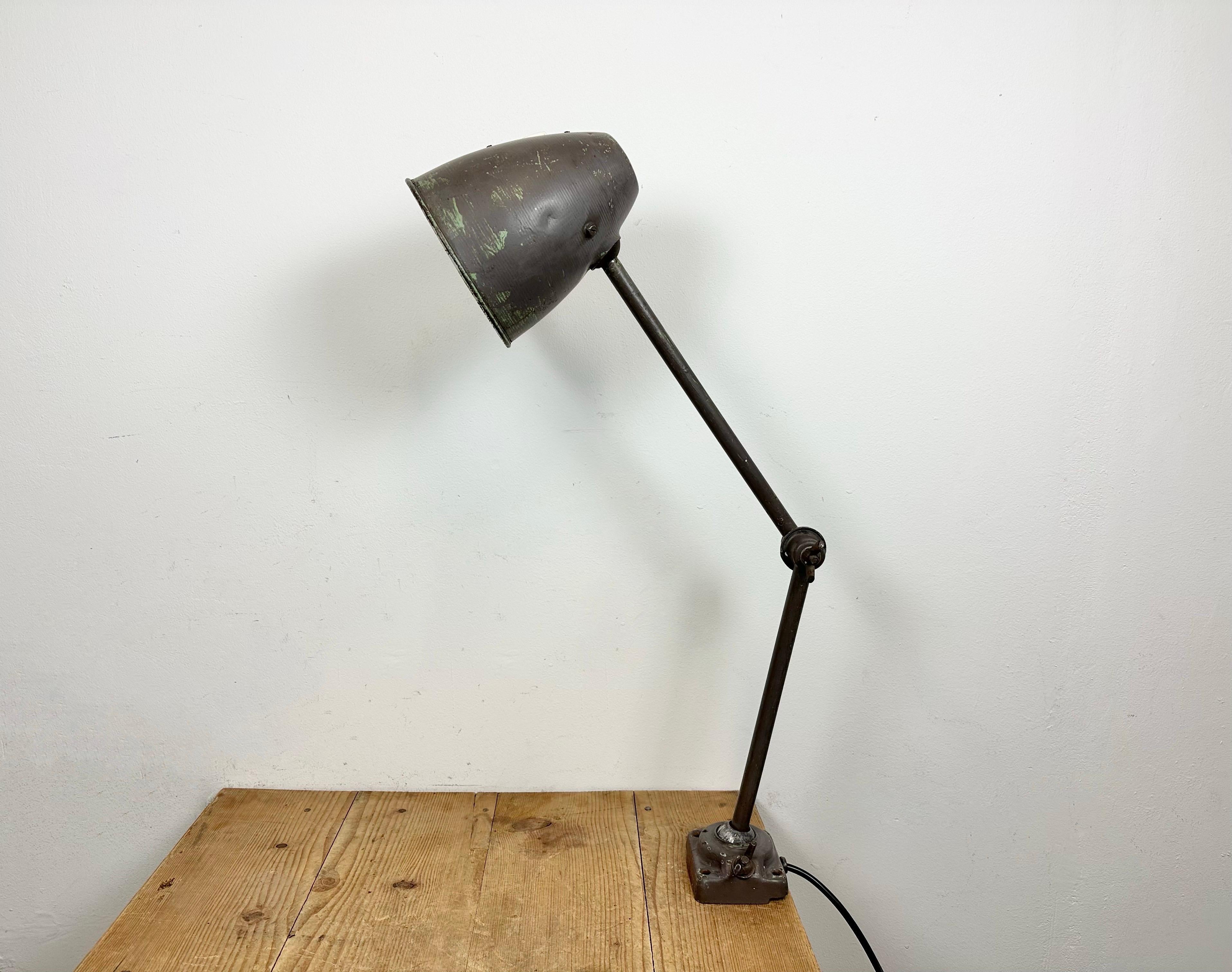 This brown industrial desk lamp was made in former Czechoslovakia during the 1960s. It features an iron body with three adjustable joints. The porcelain socket reqiures standard E 27/ E26 light bulbs. New wire. The switch is situated directly on the