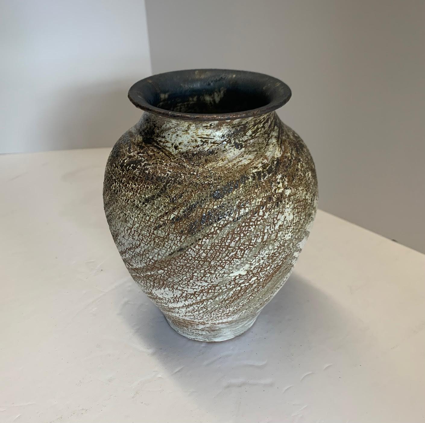 Contemporary American ceramist Peter Speliopoulos stoneware vase.
The brown stoneware vessels are slipped in black and white, and then glazed with sweeping brushstrokes in various black, ivory and bronze glazes, to create an effect of erosion, as