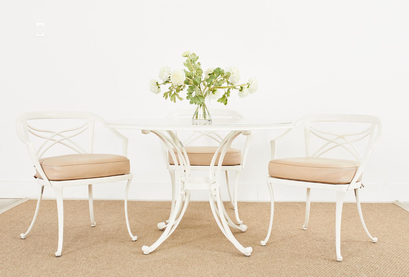 Neoclassical style aluminum patio and garden dining suite consisting of a dining table and four dining armchairs. Made by Brown Jordan featuring a white powder coated finish over a cast aluminum frame. The round table is 42 inches in diameter and