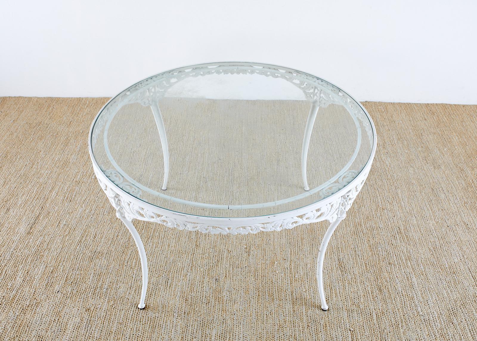 Elegant set of four dining chairs and a round patio and garden dining table made by Brown Jordan. Made in the neoclassical taste featuring klismos style legs and acanthus motif designs. Crafted from multi-step powder-coated aluminum and finish in