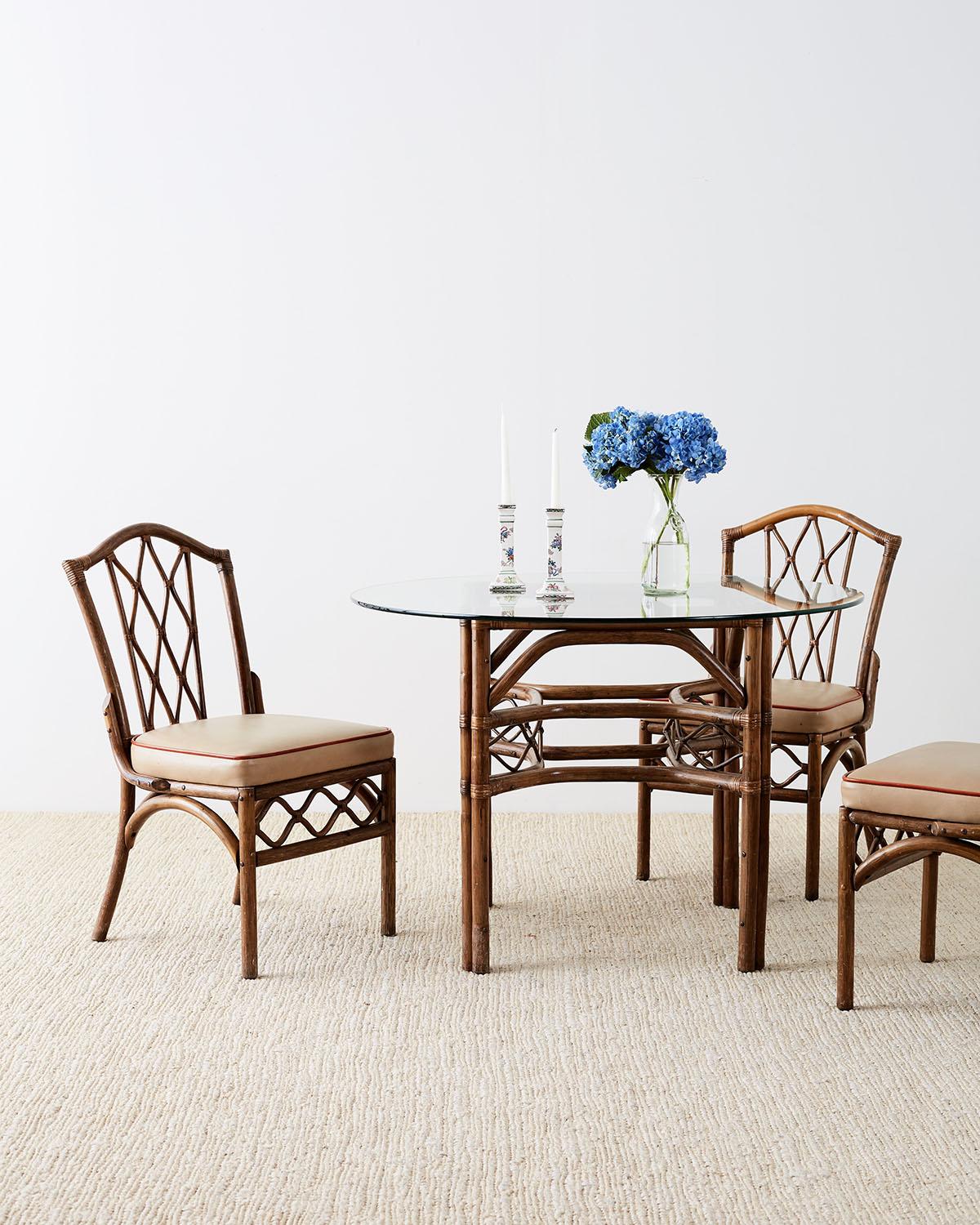 Organic modern style Brown Jordan round dining table or breakfast table. Constructed from bamboo and rattan frame decorated with stretchers having a lattice design on each side. Topped with a pane of round glass and supported by double rattan legs.