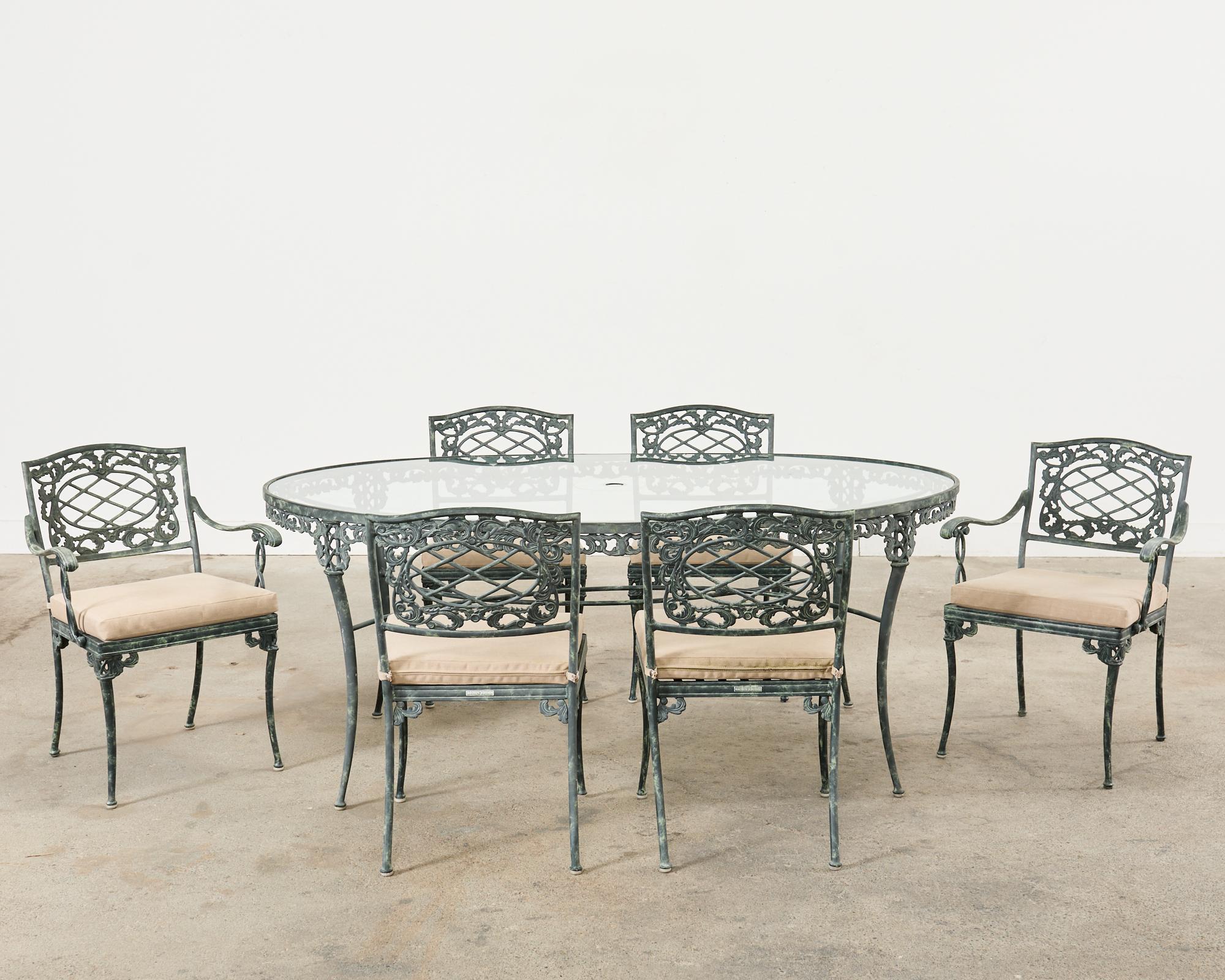 Opulent patio and garden dining suite consisting of six dining chairs and an oval umbrella table. Crafted by Brown Jordan artisans part of the Elegance collection featuring a rare bespoke custom-ordered optional verdigris finish. There are four side