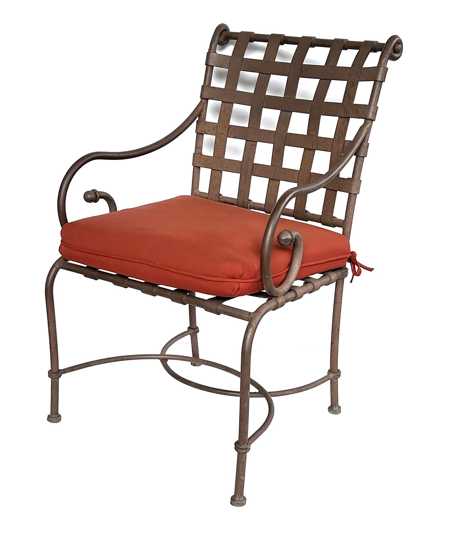 Consisting of a round glass top table and four armchairs with openwork metal strap-work manufactured by the iconic outdoor furniture manufacturer Brown Jordan;  Brown Jordan, a manufacturer of high-end outdoor furniture, was founded in Pasadena,