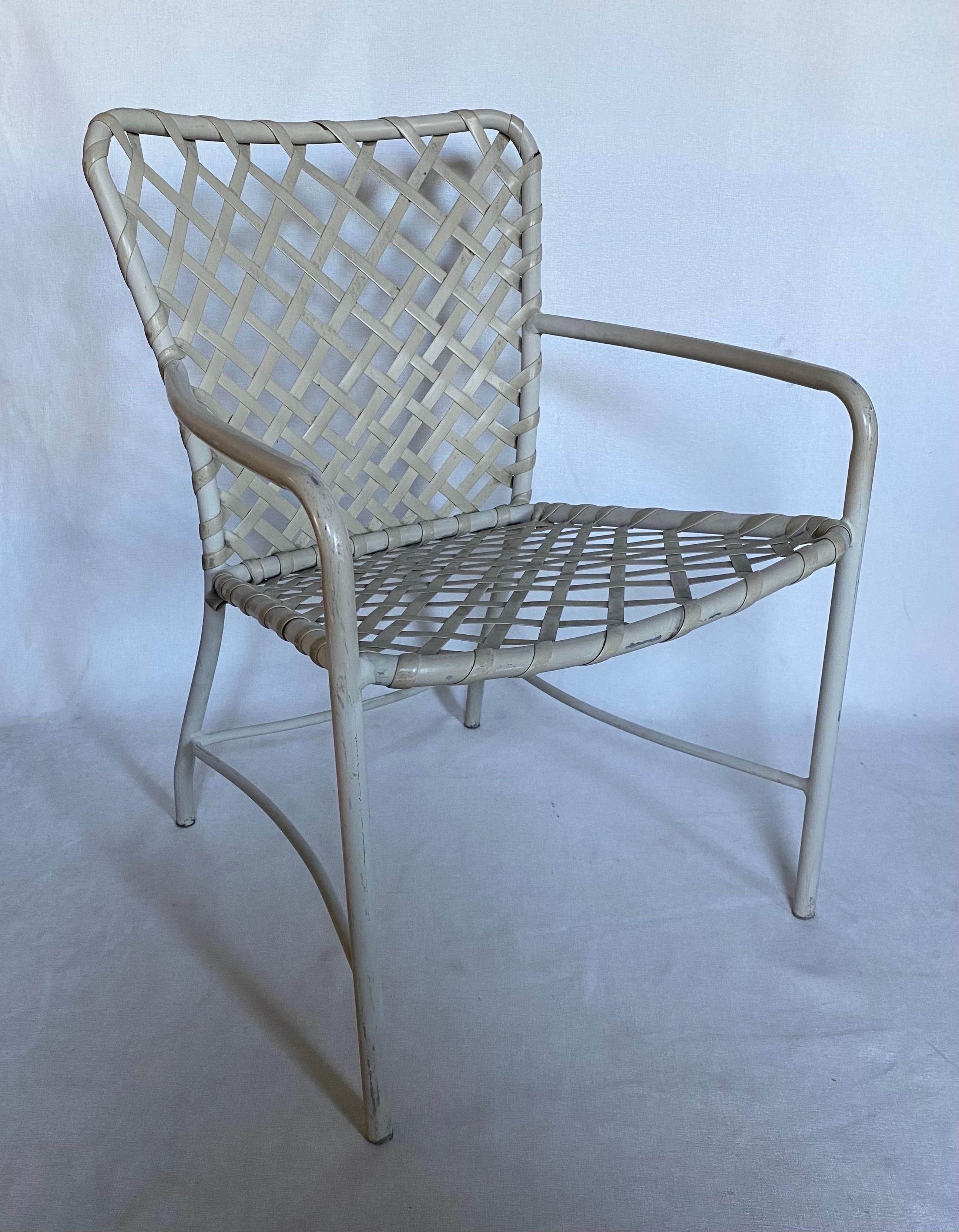 Set of four of Mid-Century Modern outdoor patio dining armchairs by Brown Jordan. White tubular curved aluminum frames feature original white/cream vinyl strapping in a cross-lace pattern. Original Brown Jordan labels and item numbers on all frames.