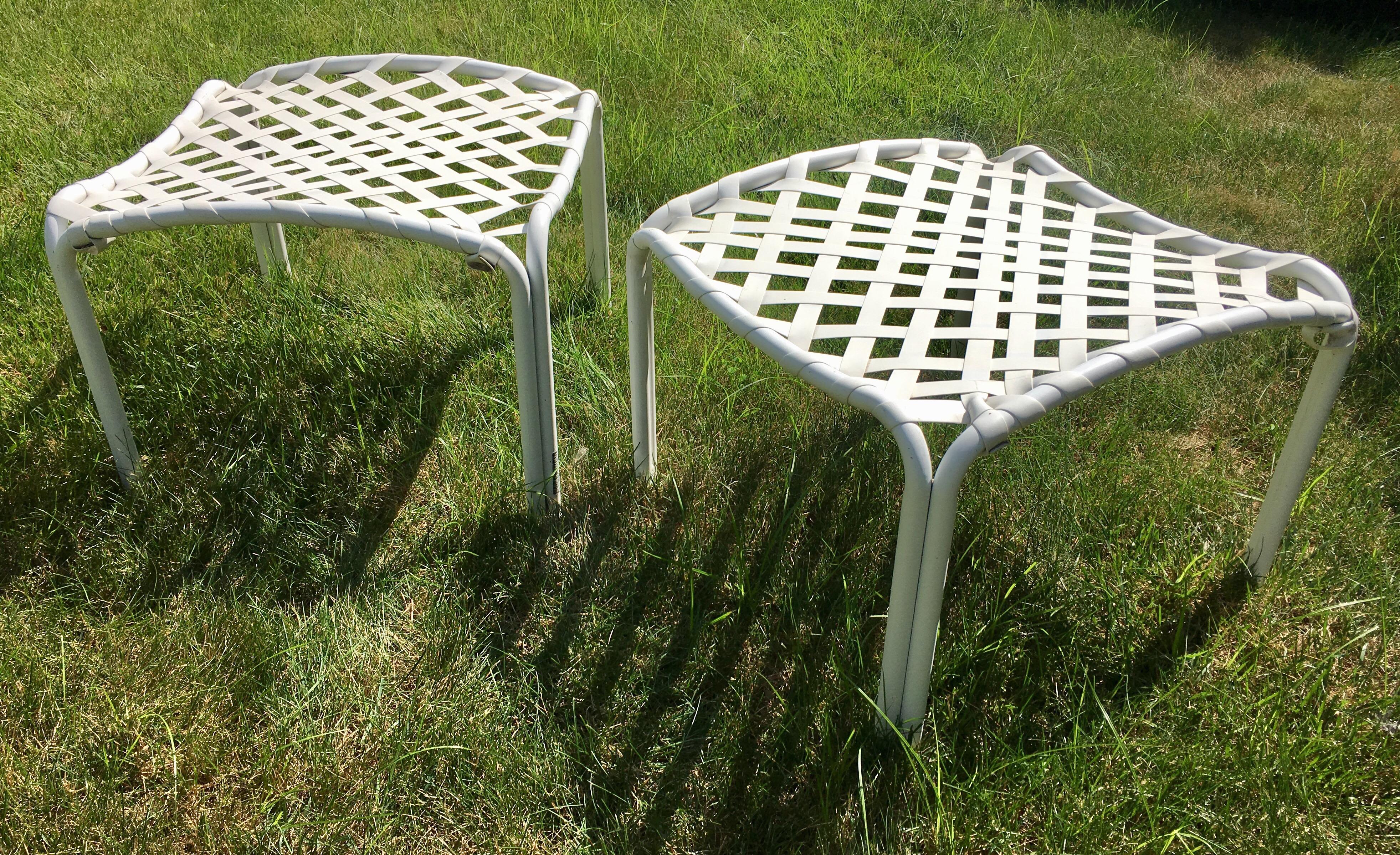 Pair of Mid-Century Modern outdoor patio or deck ottoman stools by Brown Jordan. White tubular curved aluminum frames feature original white vinyl strapping in a cross-lace pattern. Original Brown Jordan labels and item numbers on frames. Perfect