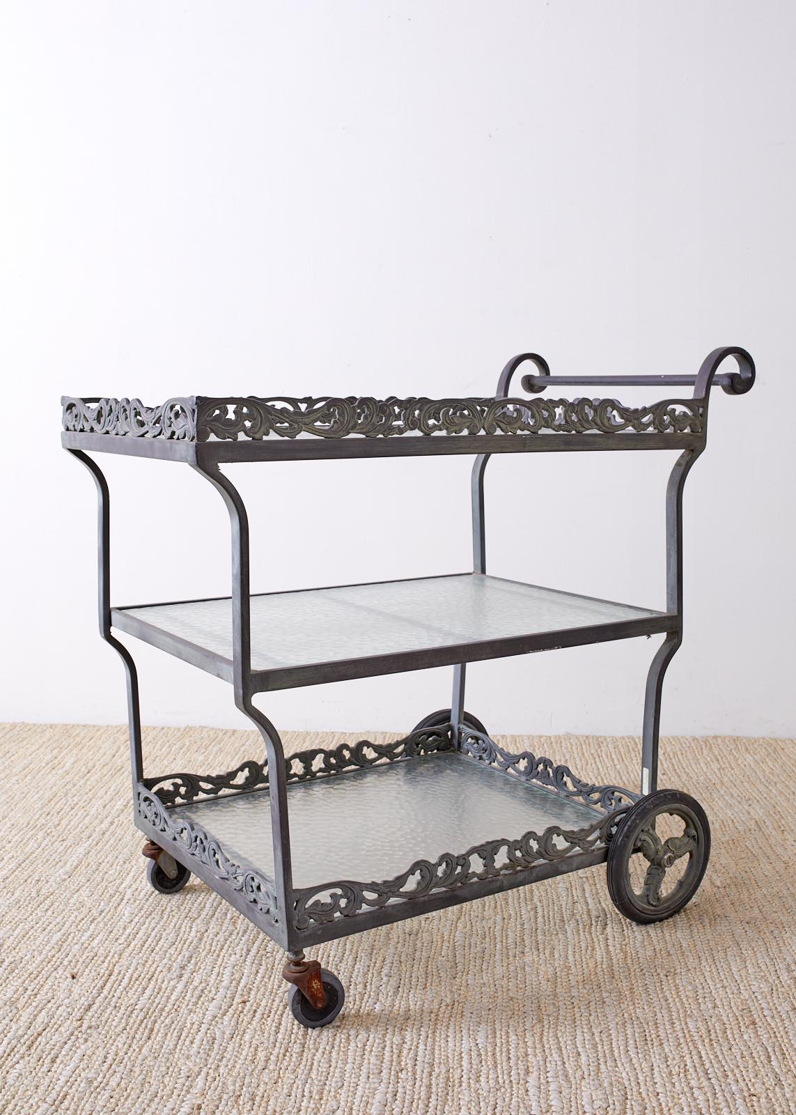 Three tier aluminum bar cart or cocktail trolley made by Brown Jordan. Features a neoclassical acanthus design motif on two of the galleried tiers. The cart has a beautiful verdigris metal patina and each tier has a textured glass inset. From an
