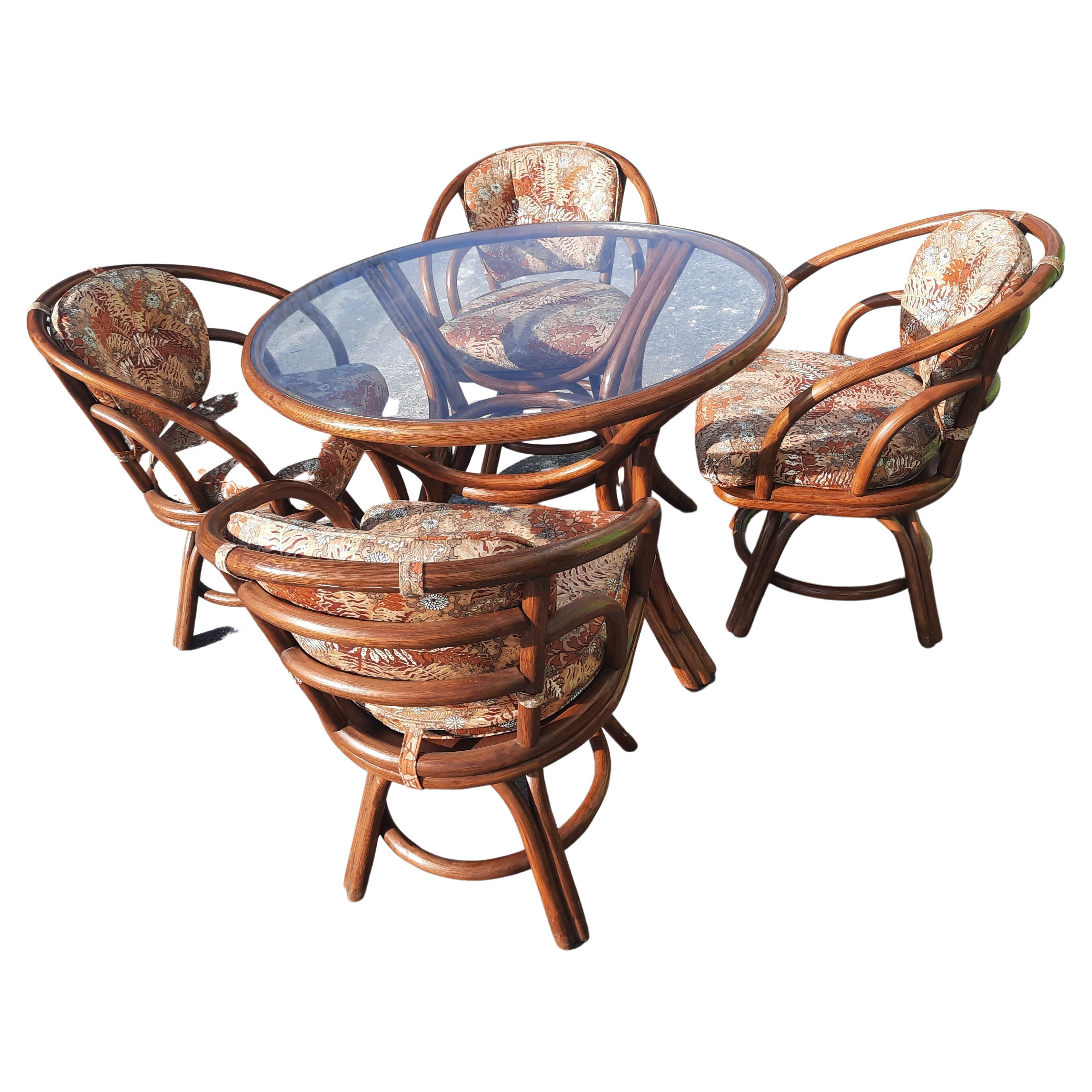 This is a stylish Rattan bentwood deco style dining or patio table and 4 chair set by Brown Jordan. It has the look of faux bamboo. Set in excellent condition. Features a glass top and arched bentwood base with an open design. The Beautiful design