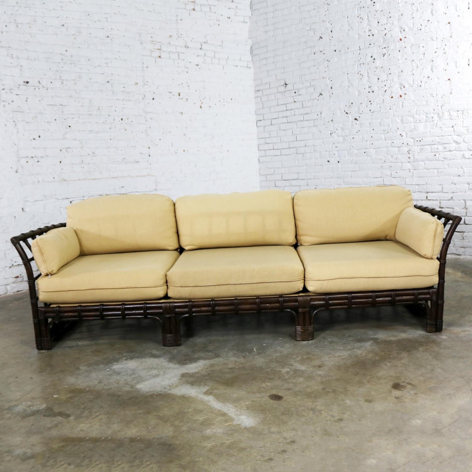 Handsome windowpane style rattan sofa by Brown Jordan with straw colored upholstered cushions. It is in wonderful vintage condition. There is slight color fading or discoloration on some of the cushions from being in the same location on the sofa