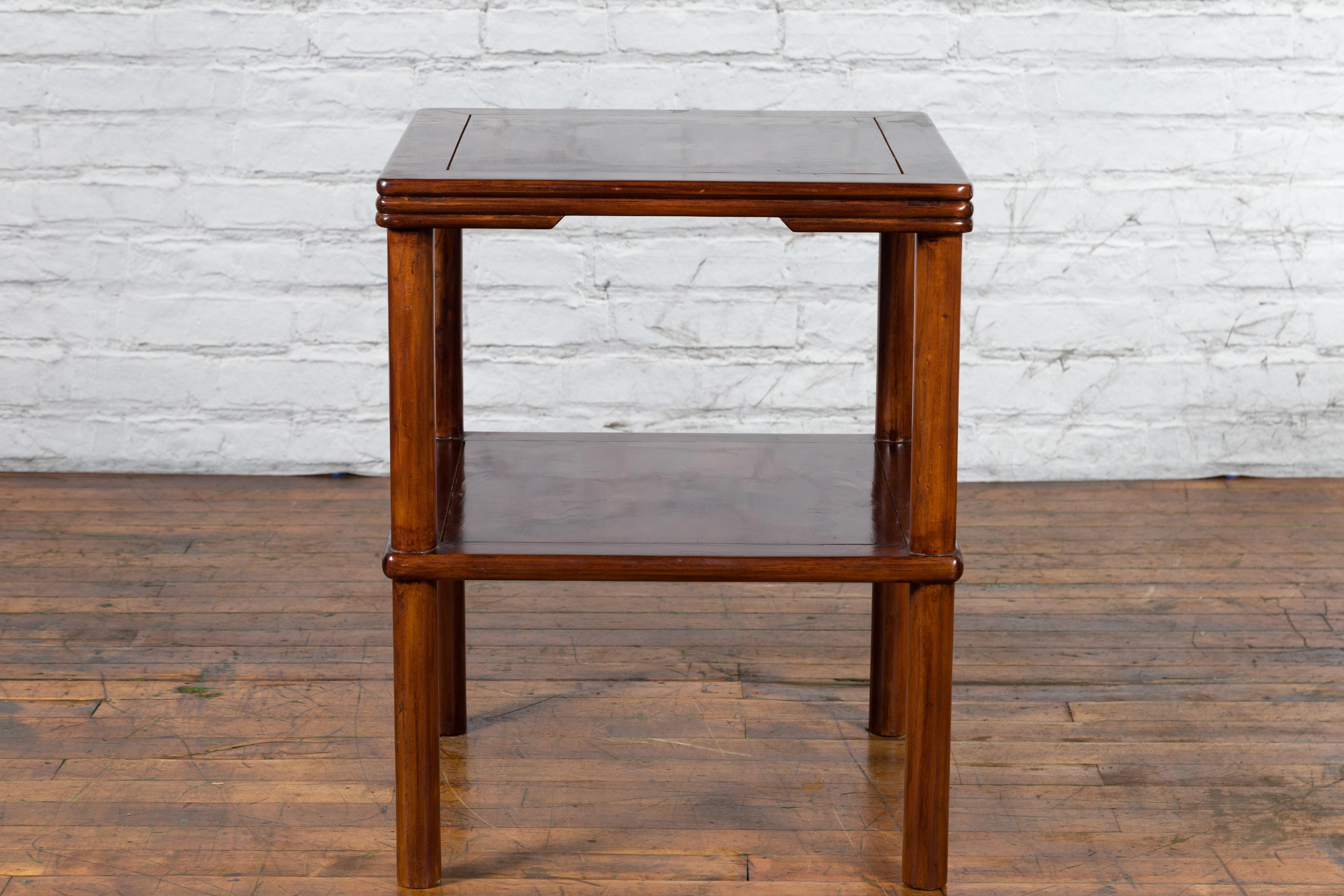 A Chinese Qing Dynasty period brown lacquered side table from the 19th century, with reeded apron. Created in China during the Qing Dynasty period, this side table features a square top with central board, sitting above a reeded apron. Raised on
