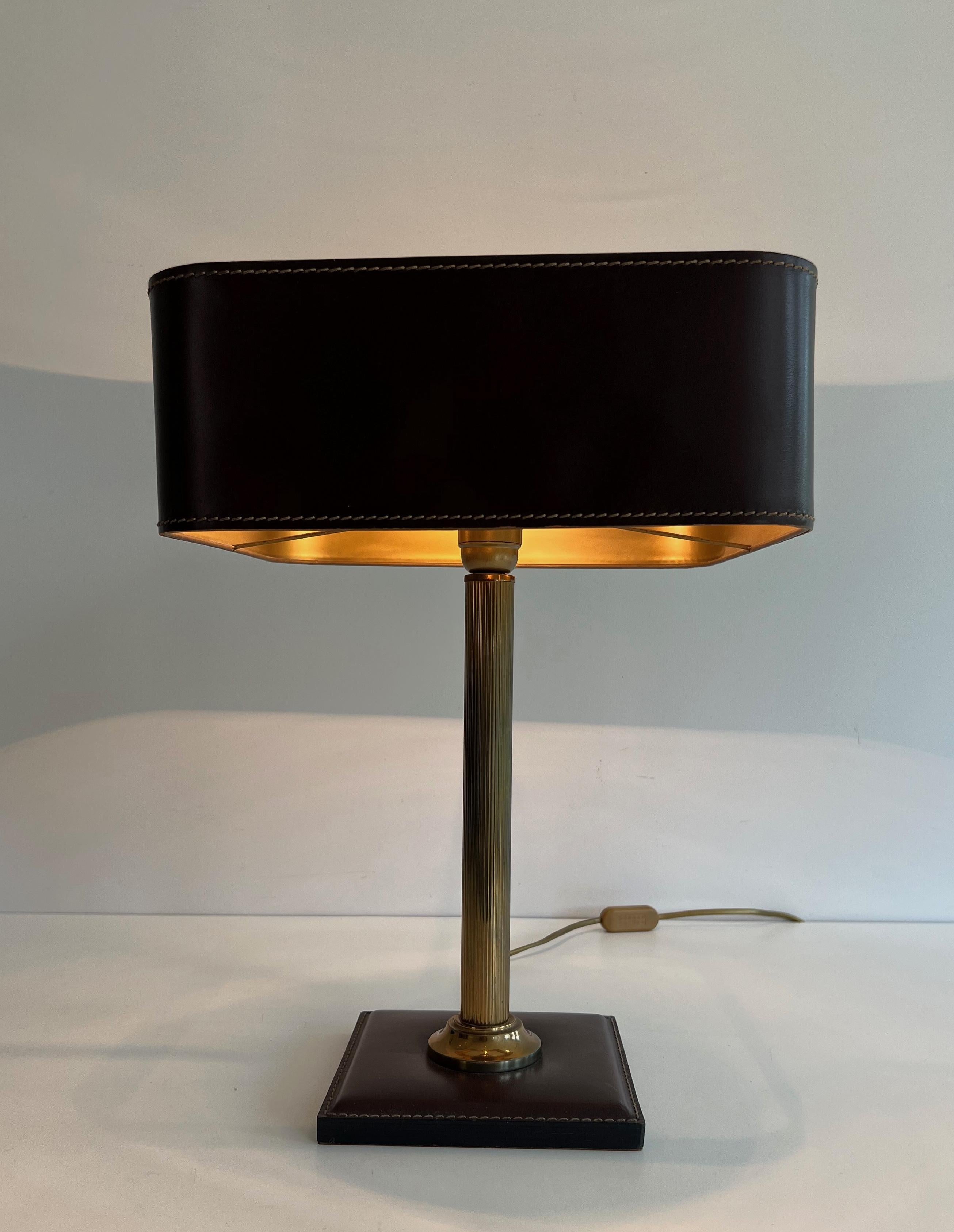 Cette jolie lampe de bureau est fabriquée en cuir brun et en laiton. Il s'agit d'une œuvre française dans le style de Jacques Adnet. Circa 1970
