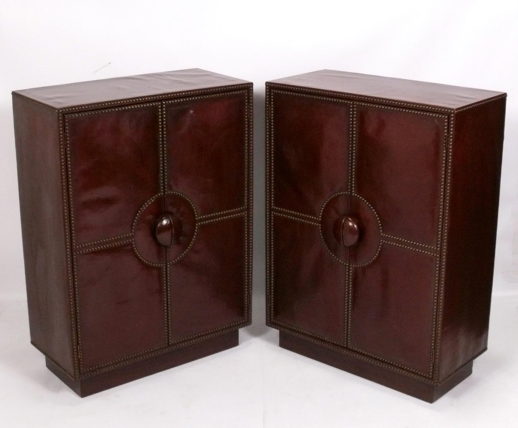 Elegant pair of brown leather and brass studded cabinets, attributed to William Billy Haynes for Sturgis, unsigned, American, circa 1930s. They are priced at $2800 each, or $4800 for the pair. They offer a voluminous amount of storage, with the left